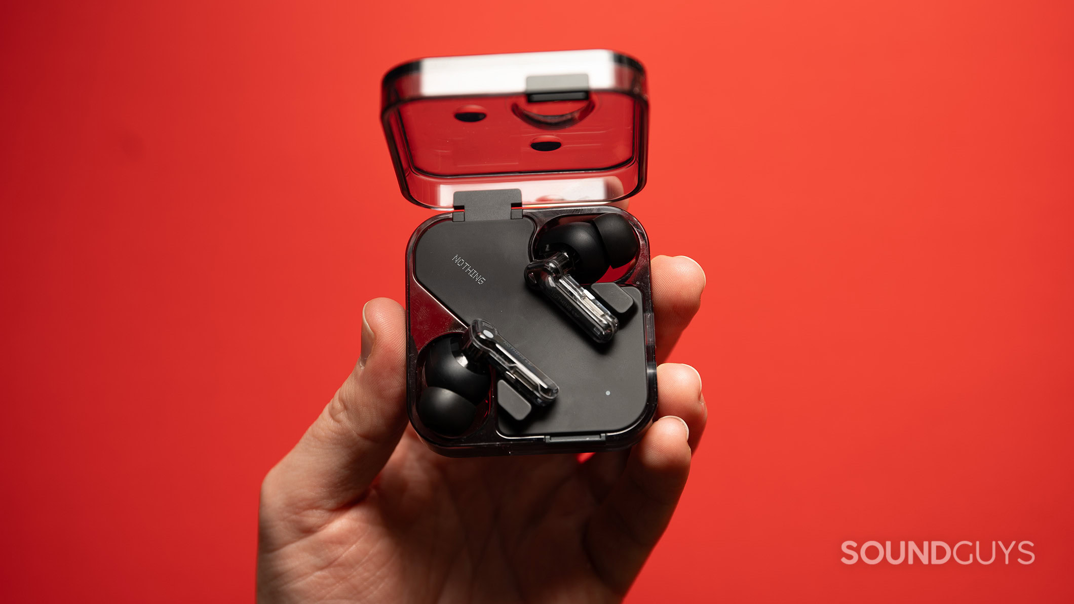 A hand holds the Nothing Ear earbuds inside the case.