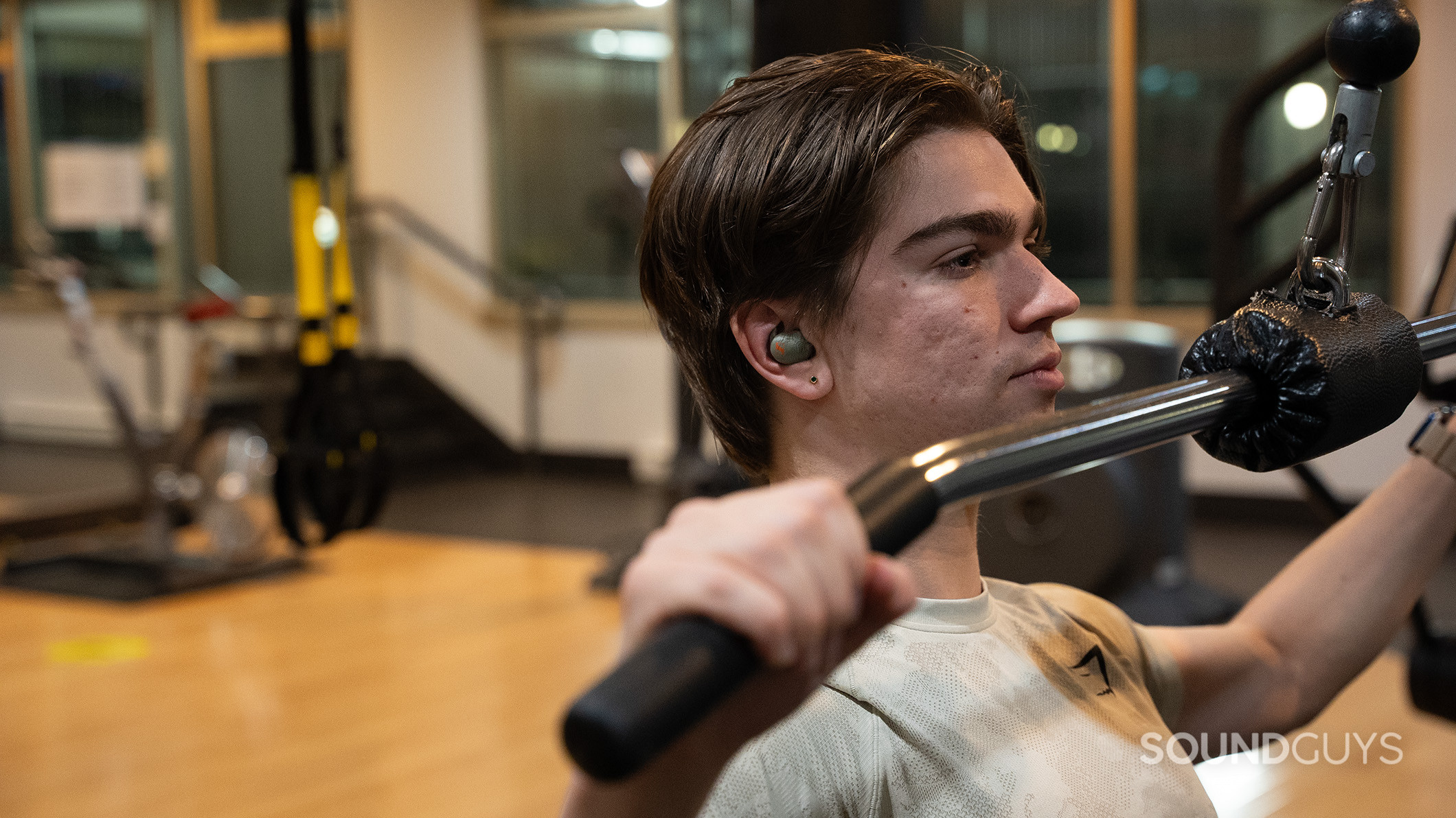 A man wearing the Sennheiser MOMENTUM Sport earbuds while exercising in a gym.