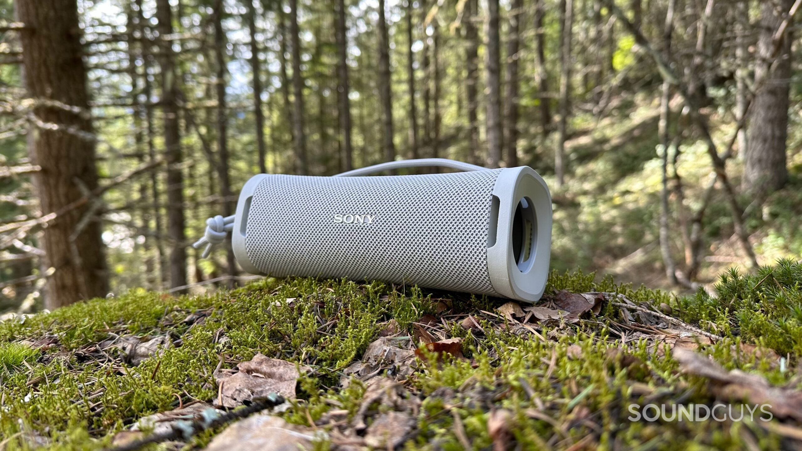 The Sony ULT Field 1 speaker facing to the left on a mossy mountainside rock.