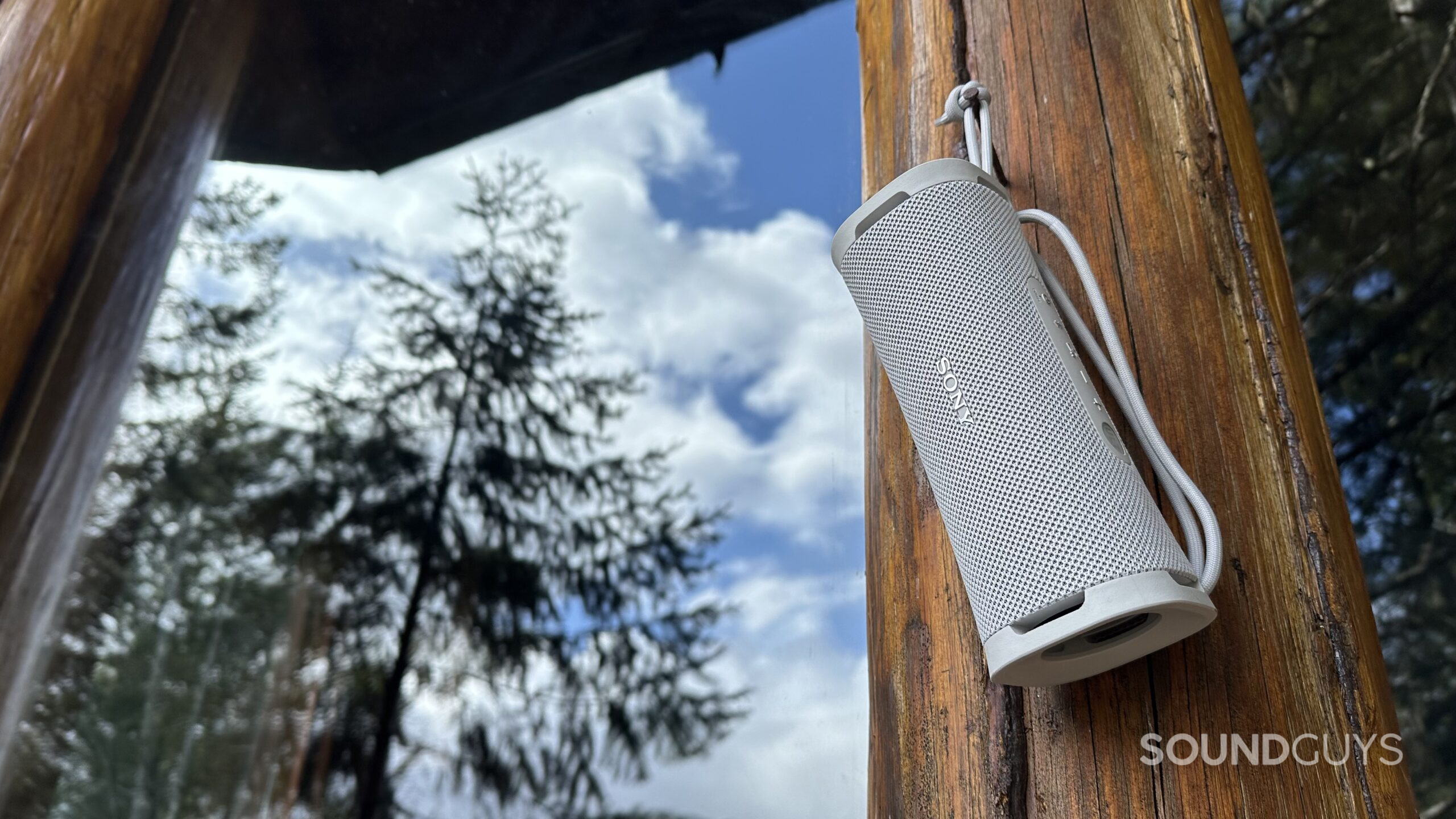 The Sony ULT Field 1 speaker hanging from a nail on the outside of a cabin.