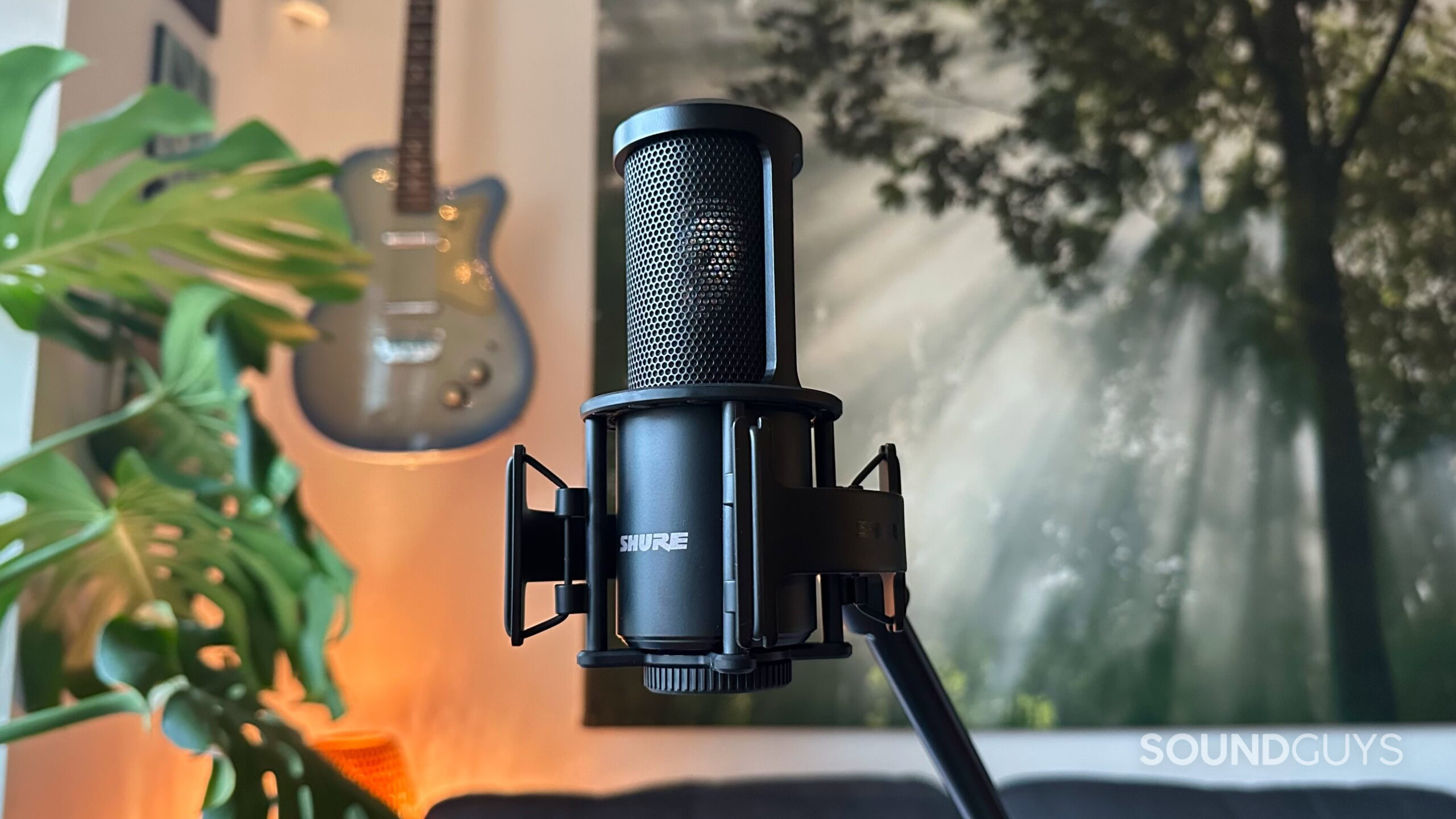 Shure SM4_hero A Shure SM4 microphone mounted on a mic stand with a guitar in the background.
