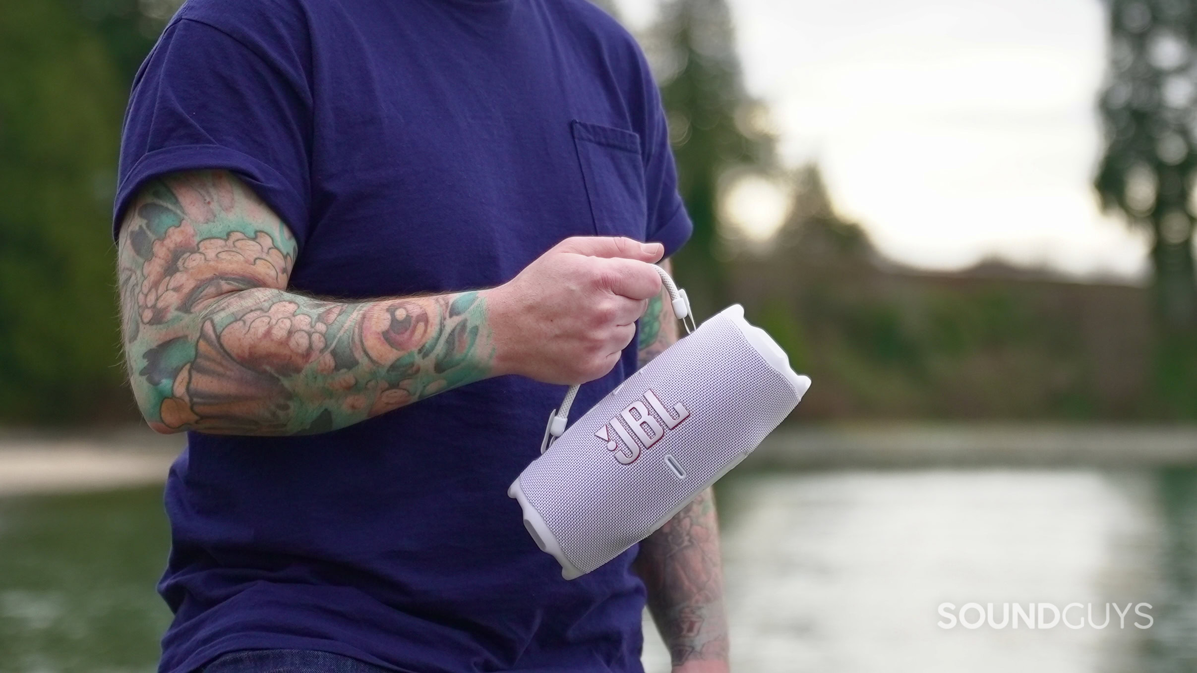 A man holding the JBL Charge 6 by its handle at the beach.