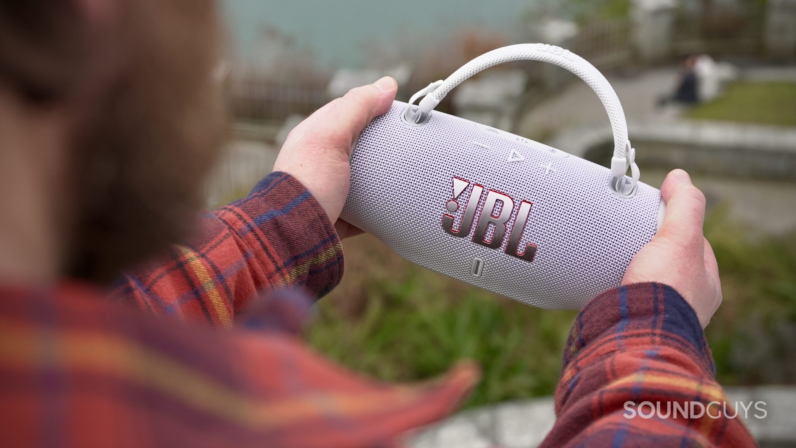A man holding a JBL Charge 6 speaker but its sides.