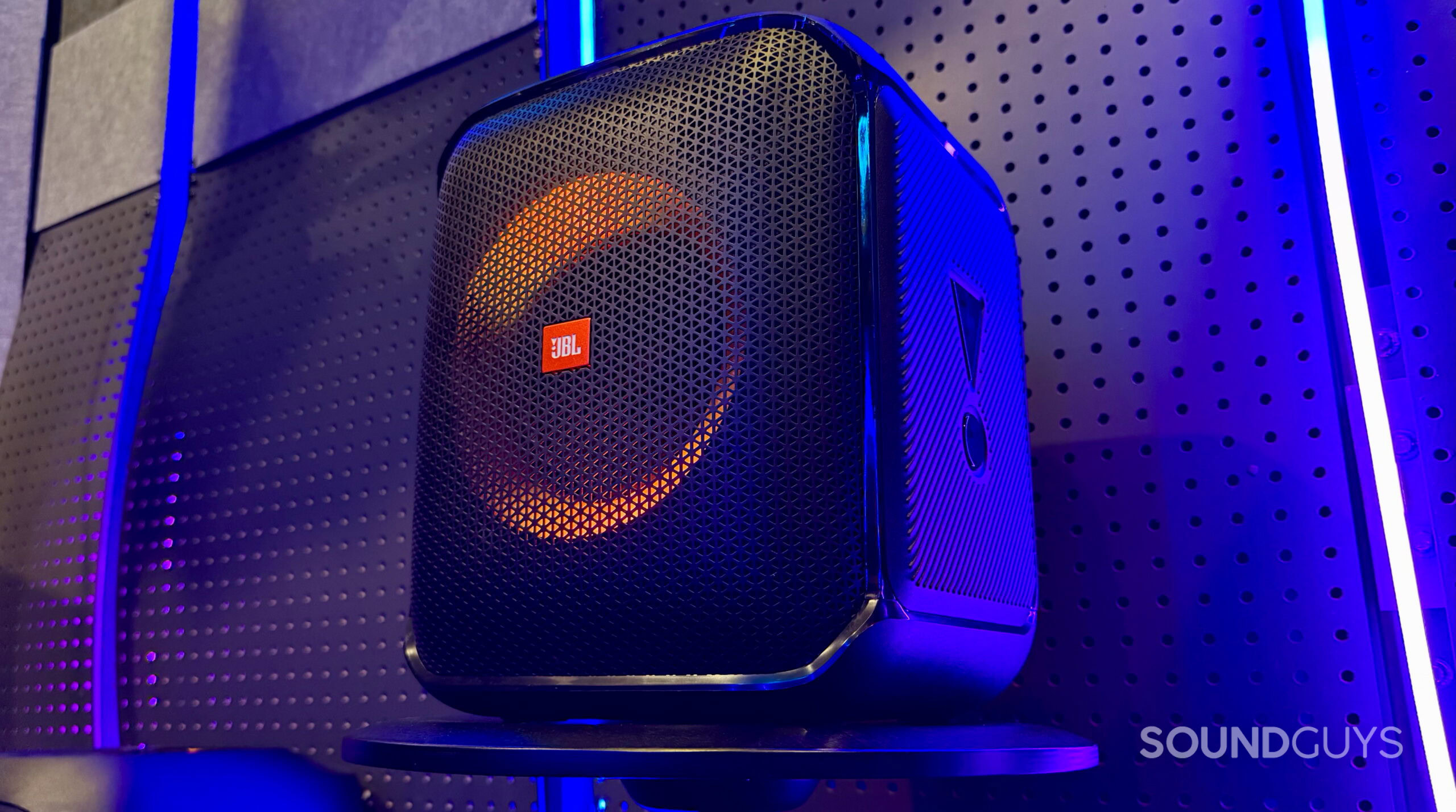 Encore PartyBox - 2 A JBL PartyBox Encore Essential speaker on a stool with neon lights in the background