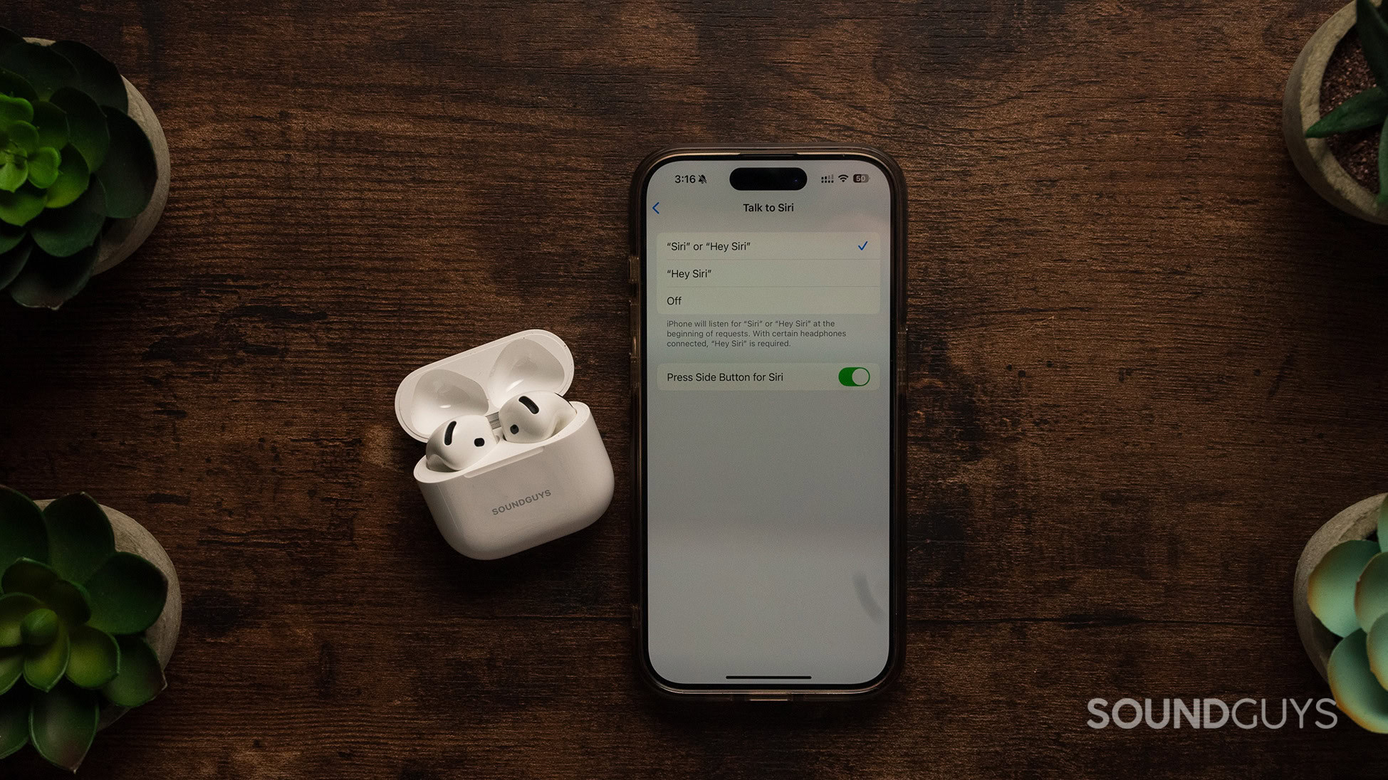 AirPods sitting beside an iPhone with Siri settings on screen.