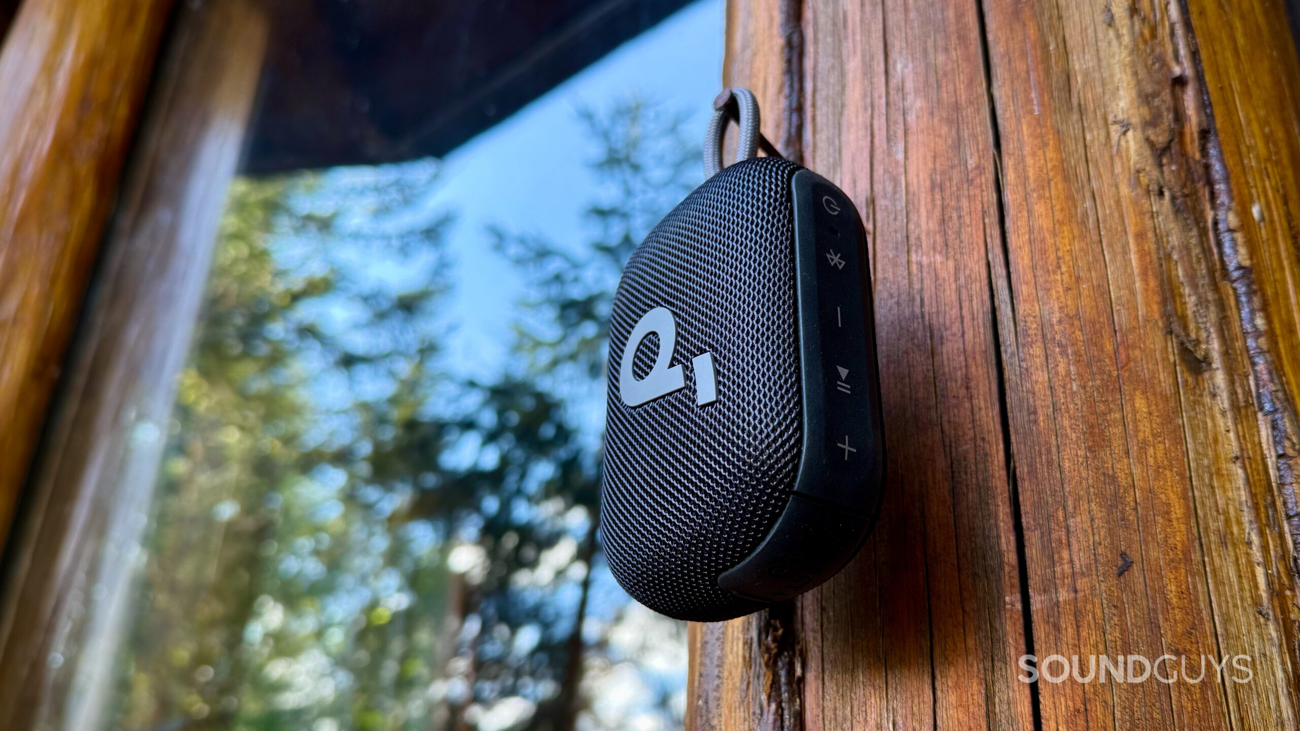 Select 4 Go - 3 A Soundcore Select 4 Go speaker hanging from its loop attachment outside a cabin.