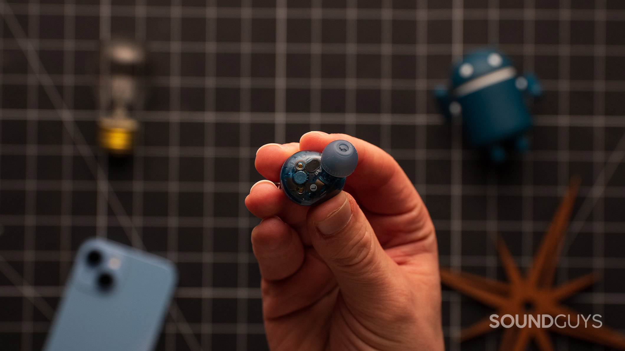 A hand holds a Sony WF-C710N earbud. 