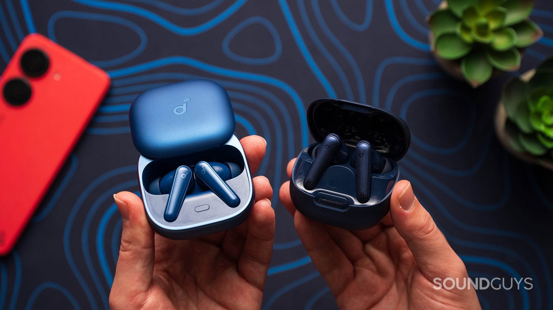 Anker Soundcore Liberty 5 next to Liberty 4 NC earbuds in case in hand Anker Soundcore Liberty 5 next to Liberty 4 NC earbuds in their charging case.