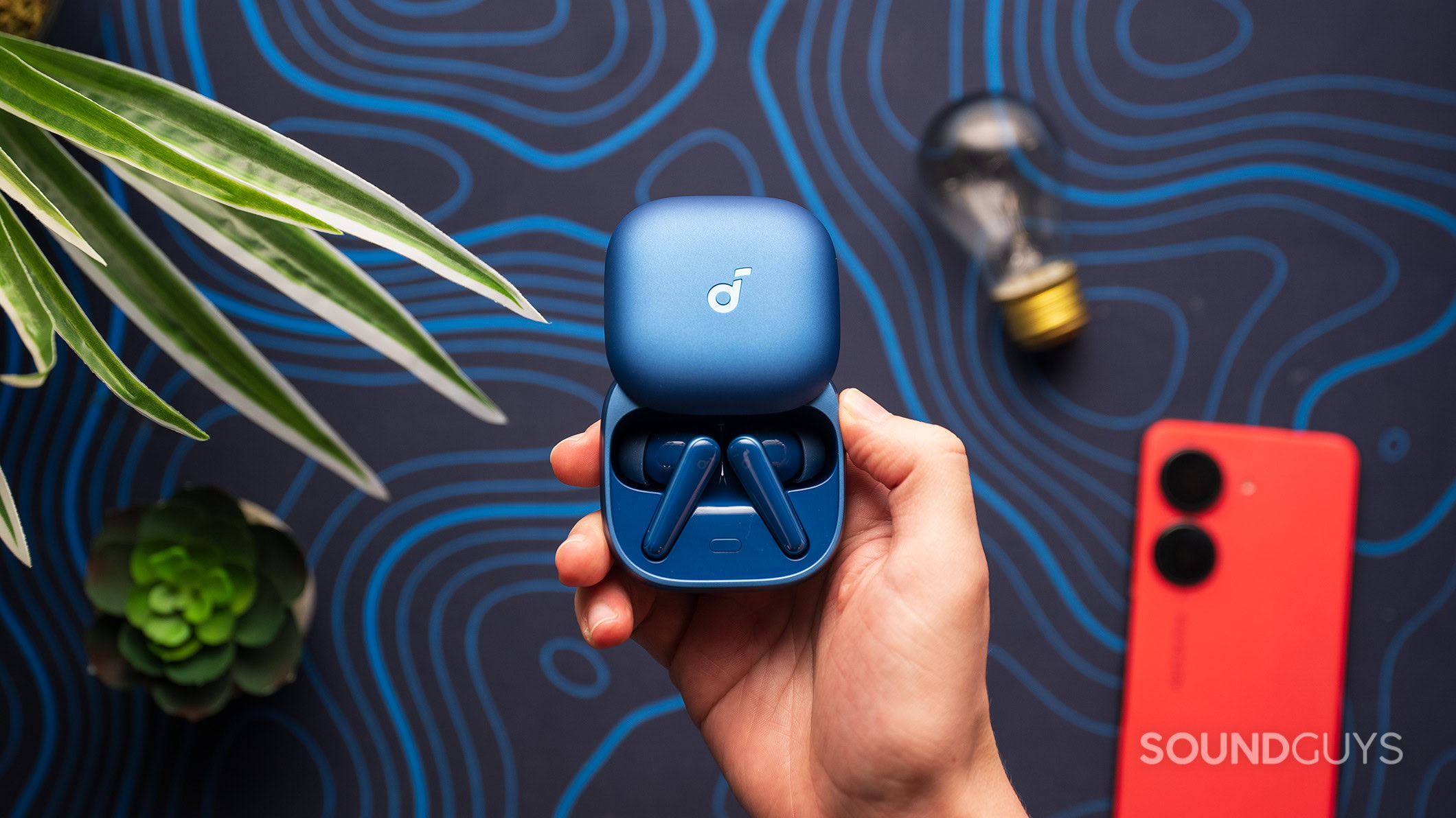 Liberty 5 earbuds in case A hand holding the Anker Soundcore Liberty 5 earbuds in their charging case.