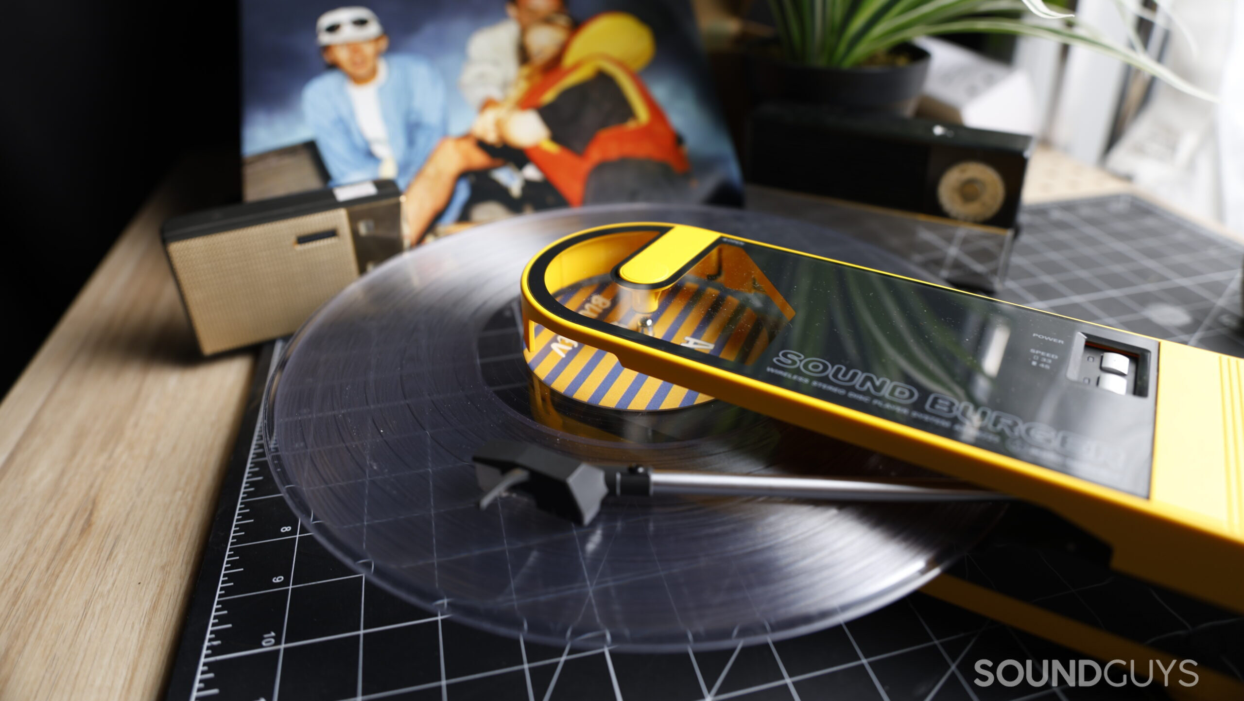 Soundburger-Clear-Hero The Audio-Technica Sound Burger sits on a table, playing a clear record. Behind it is a record sleeve and some vintage speakers.