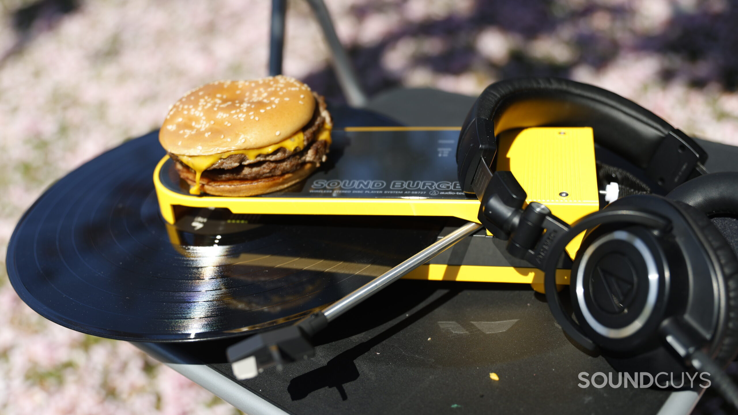 Soundburger-Grass-2 The Sound Burger sits on a chair in a field of cherry blossoms. Positioned on top is a Big Mac and a pair of Audio-Technica ATH-M50X studio headphones.