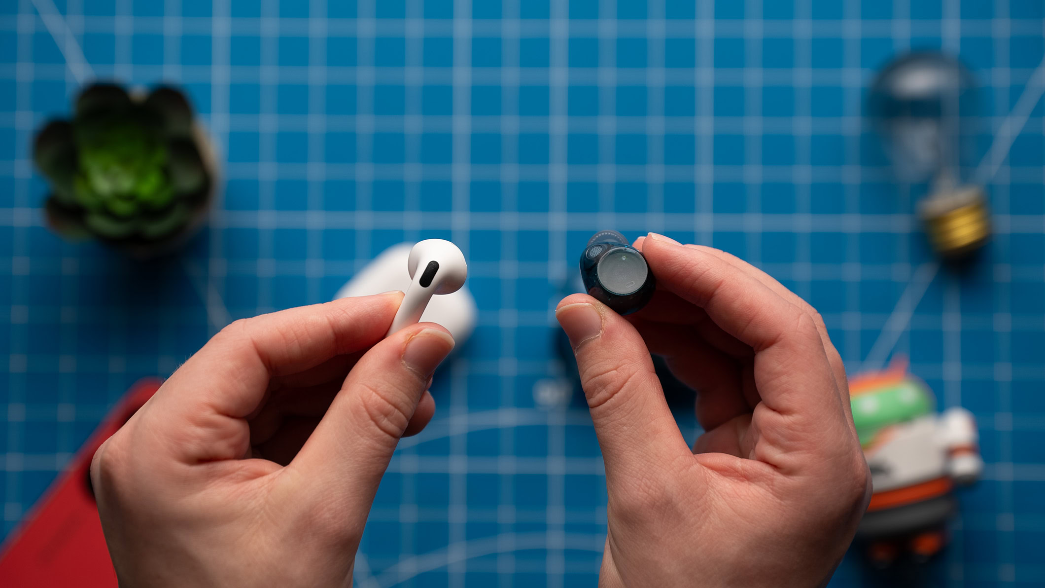 Sony WF-C710N and AirPods 4 earbud back A hand holds and AirPods 4 earbud and a Sony WF-C710N earbud.