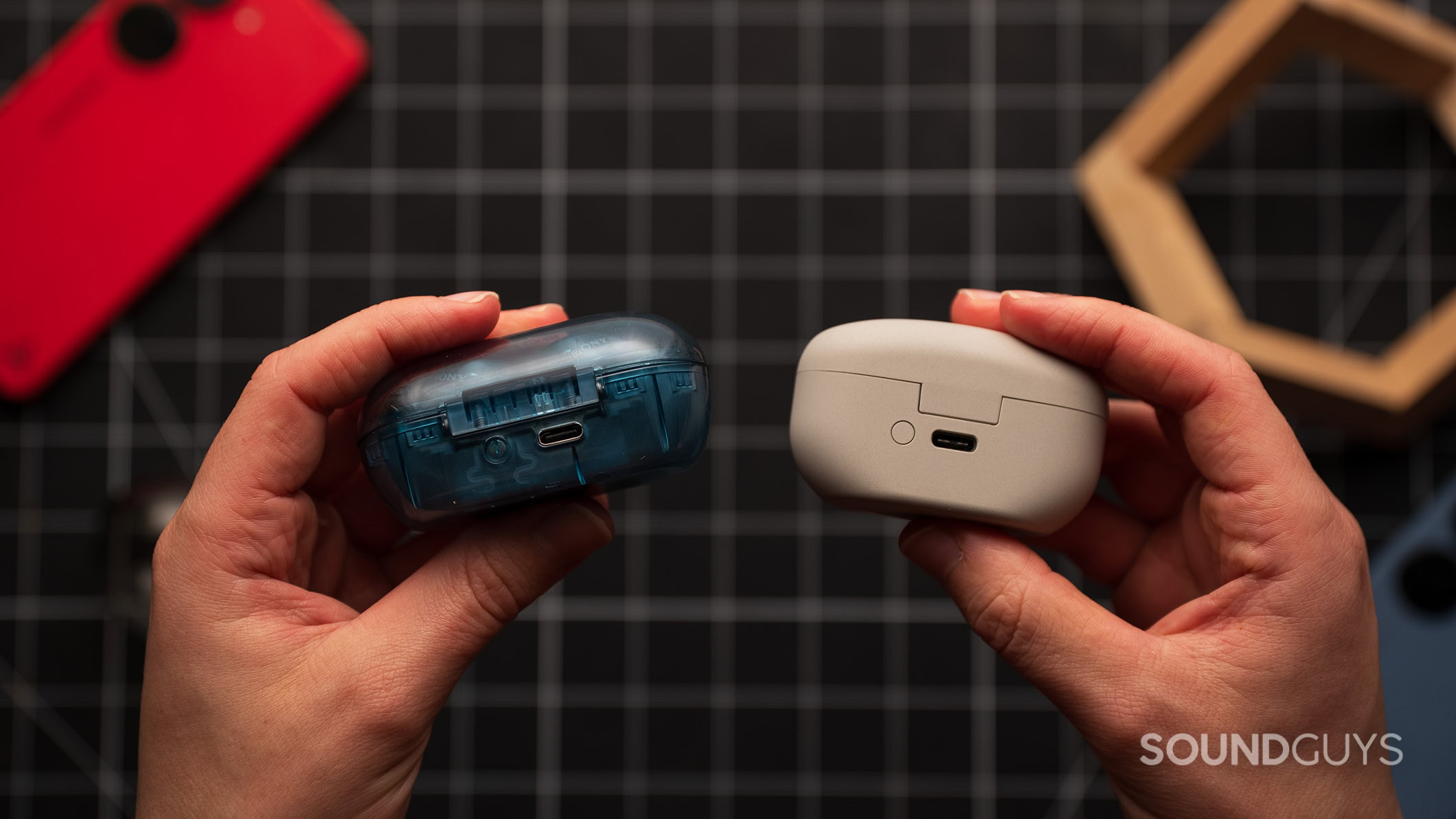 Sony WF-C710N vs Sony WF-1000XM5 charging ports Hands holding the Sony WF-1000XM5 and Sony WF-C710N earbud cases showing the charging ports.