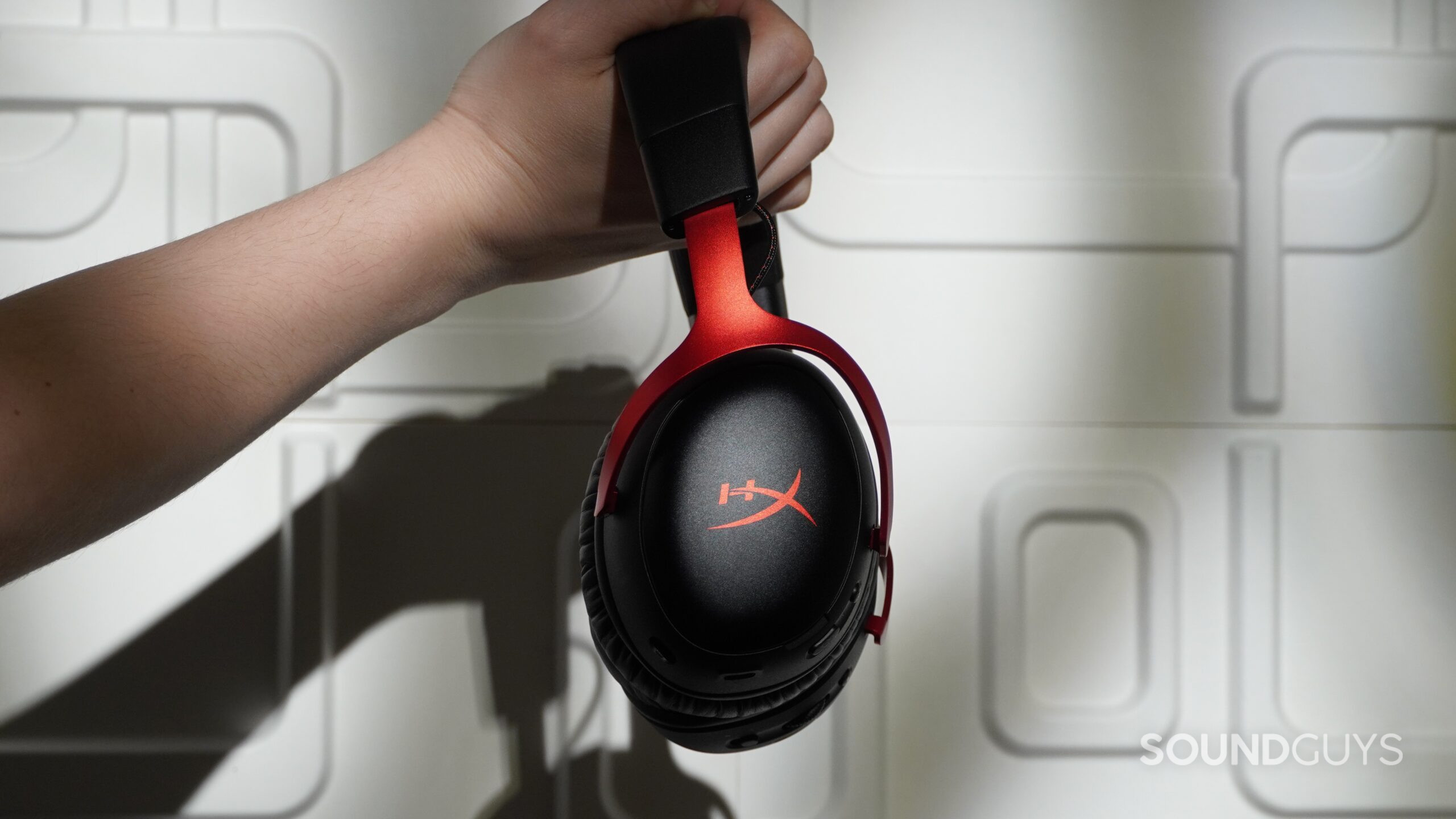 holding hyperx cloud 3 s an arm holding out the hyperx cloud 3 s