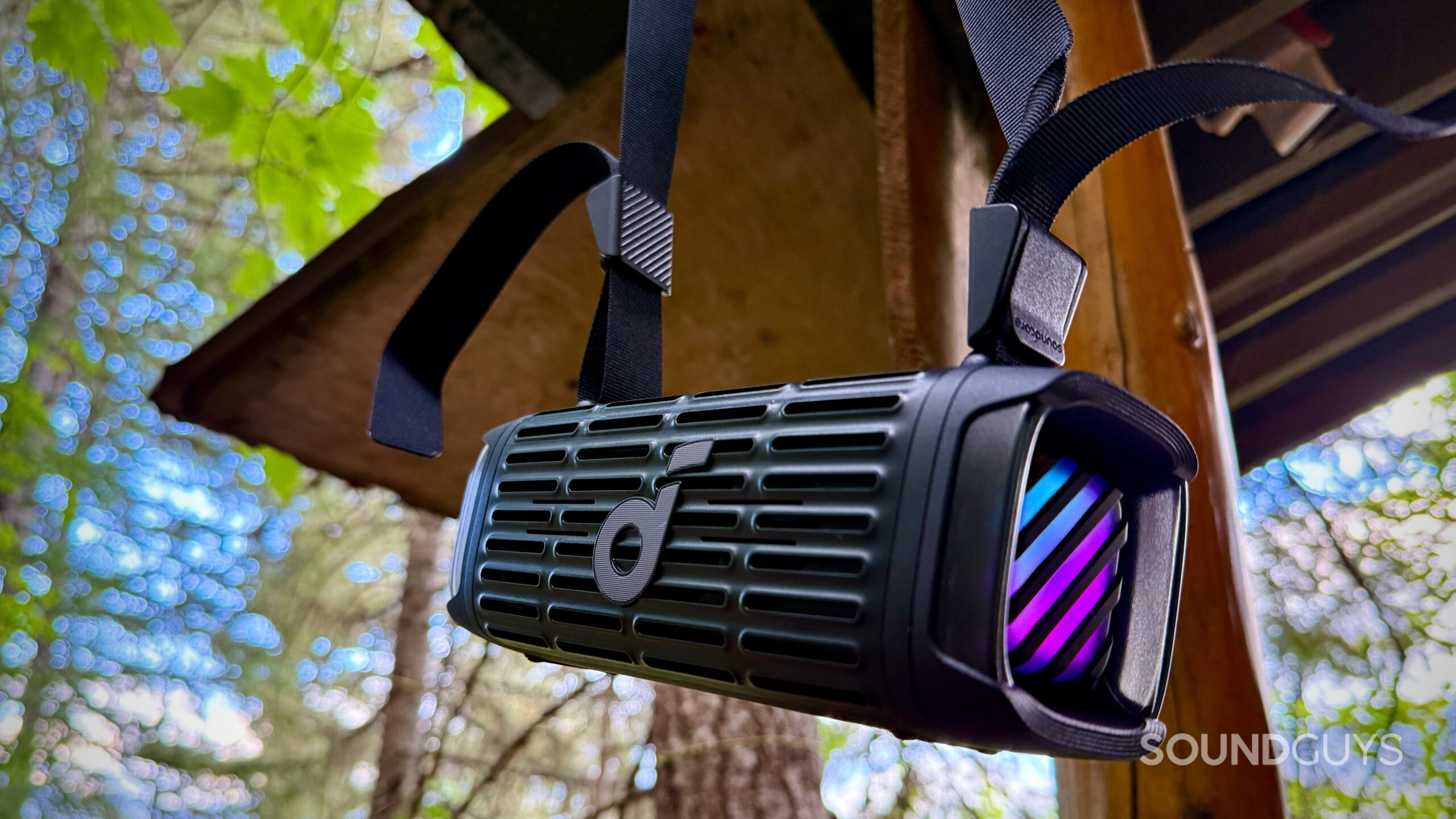 Soundcore Boom 3i hanging from its shoulder strap outdoors.
