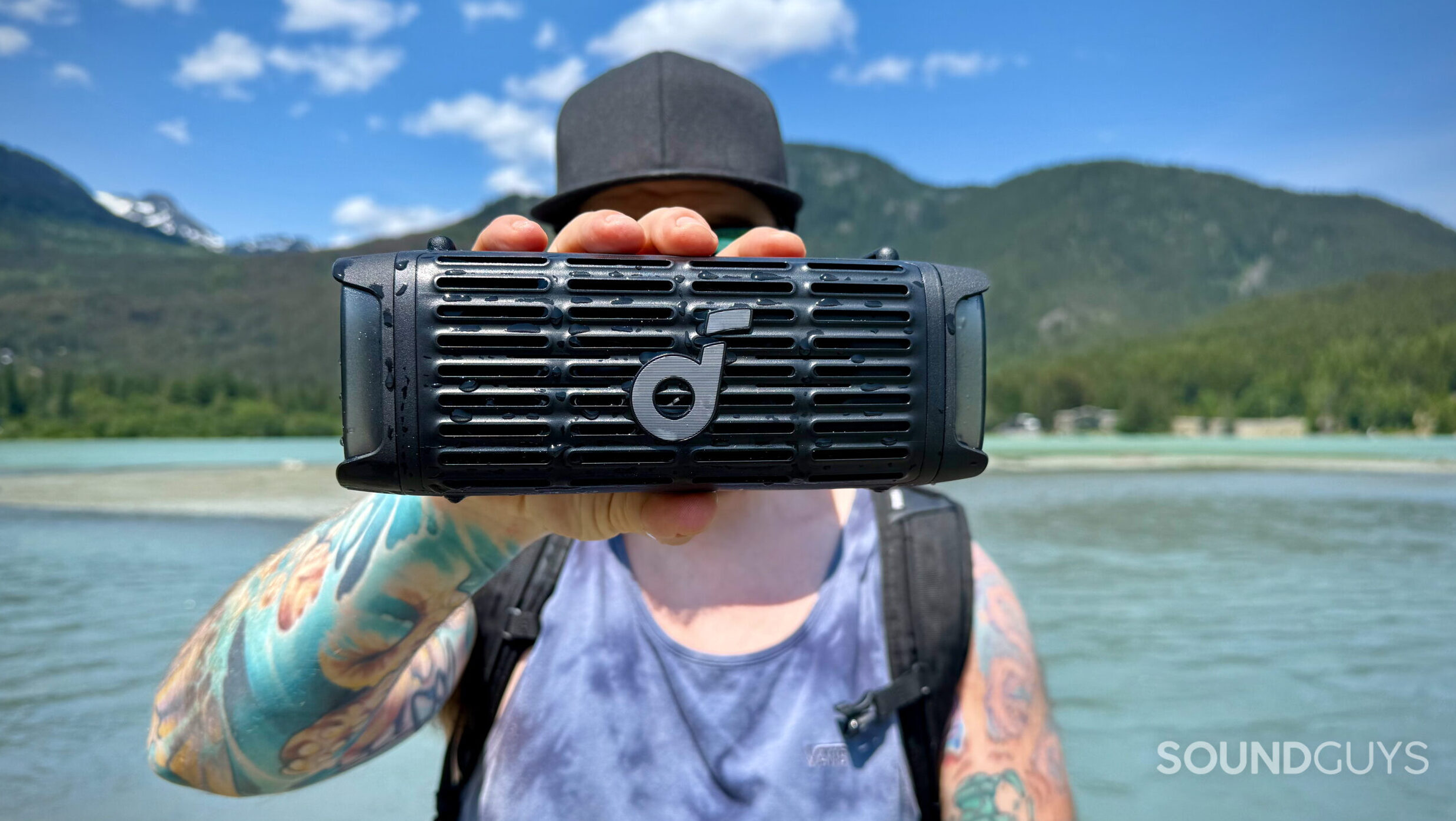 A man holding the Soundcore Boom 3i outdoors by a lake.