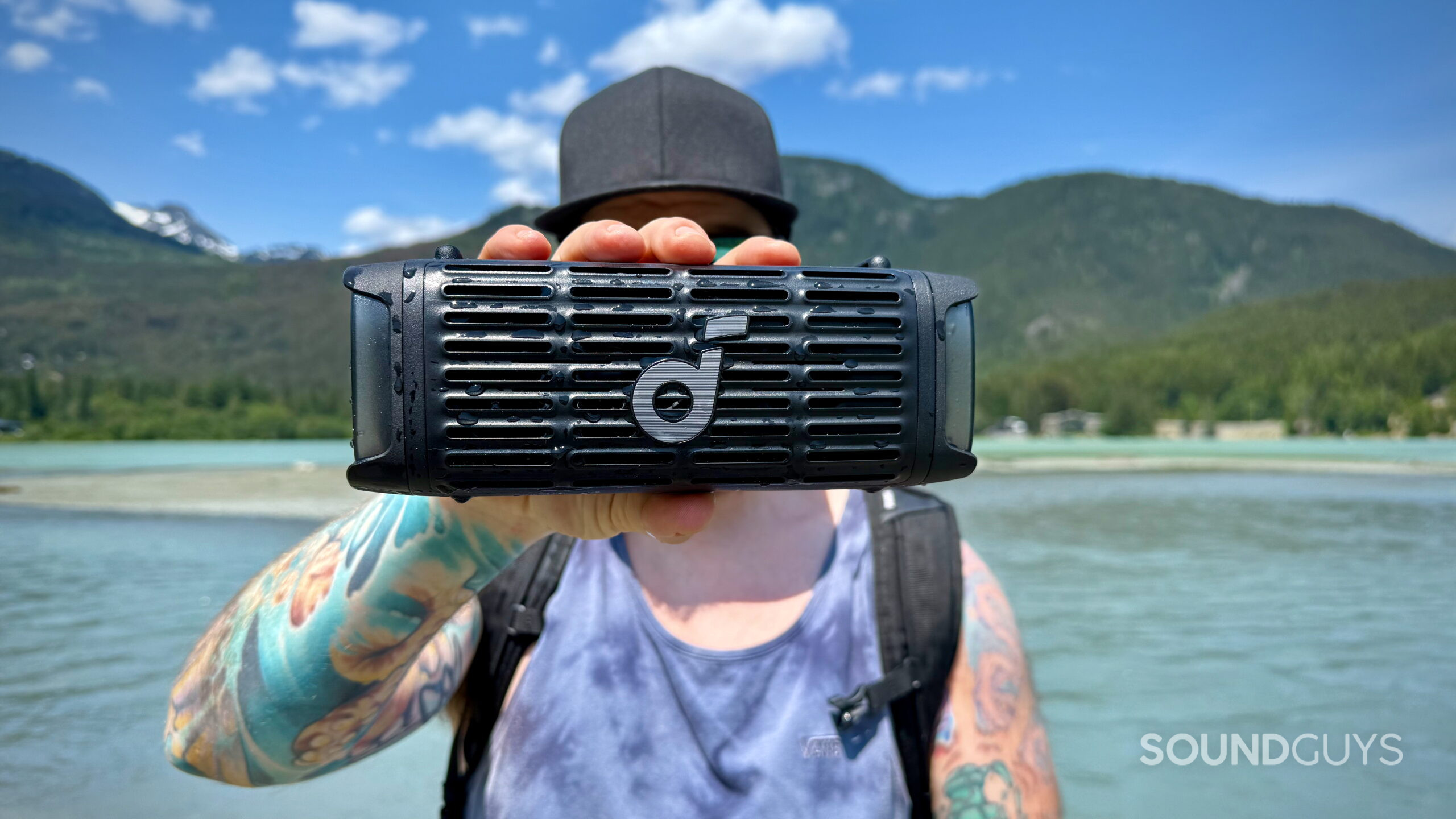 Boom 3i - 5 A man holding the Soundcore Boom 3i outdoors by a lake.