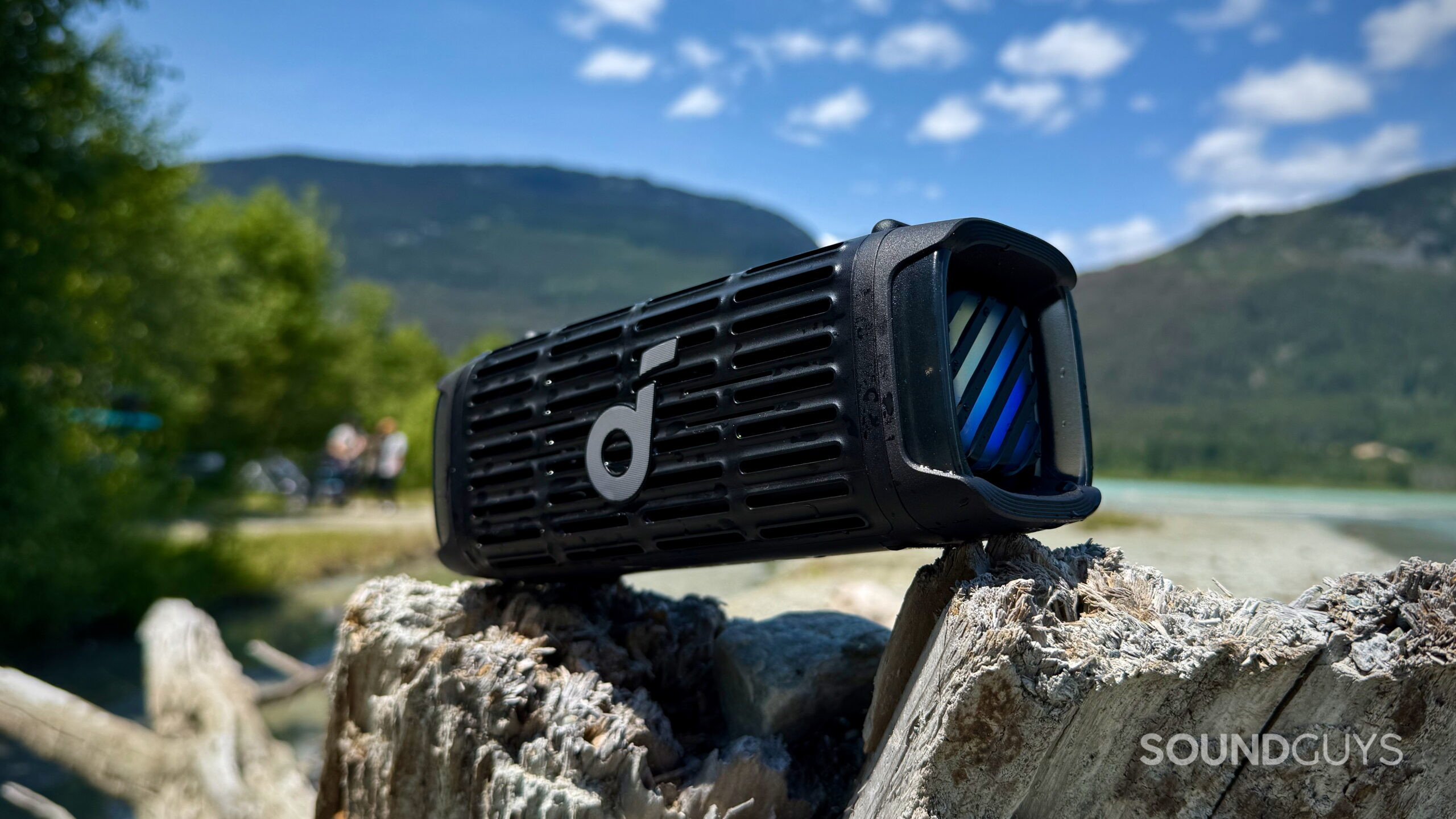 Boom 3i - 6 Soundcore Boom 3i placed on a log by the lake.