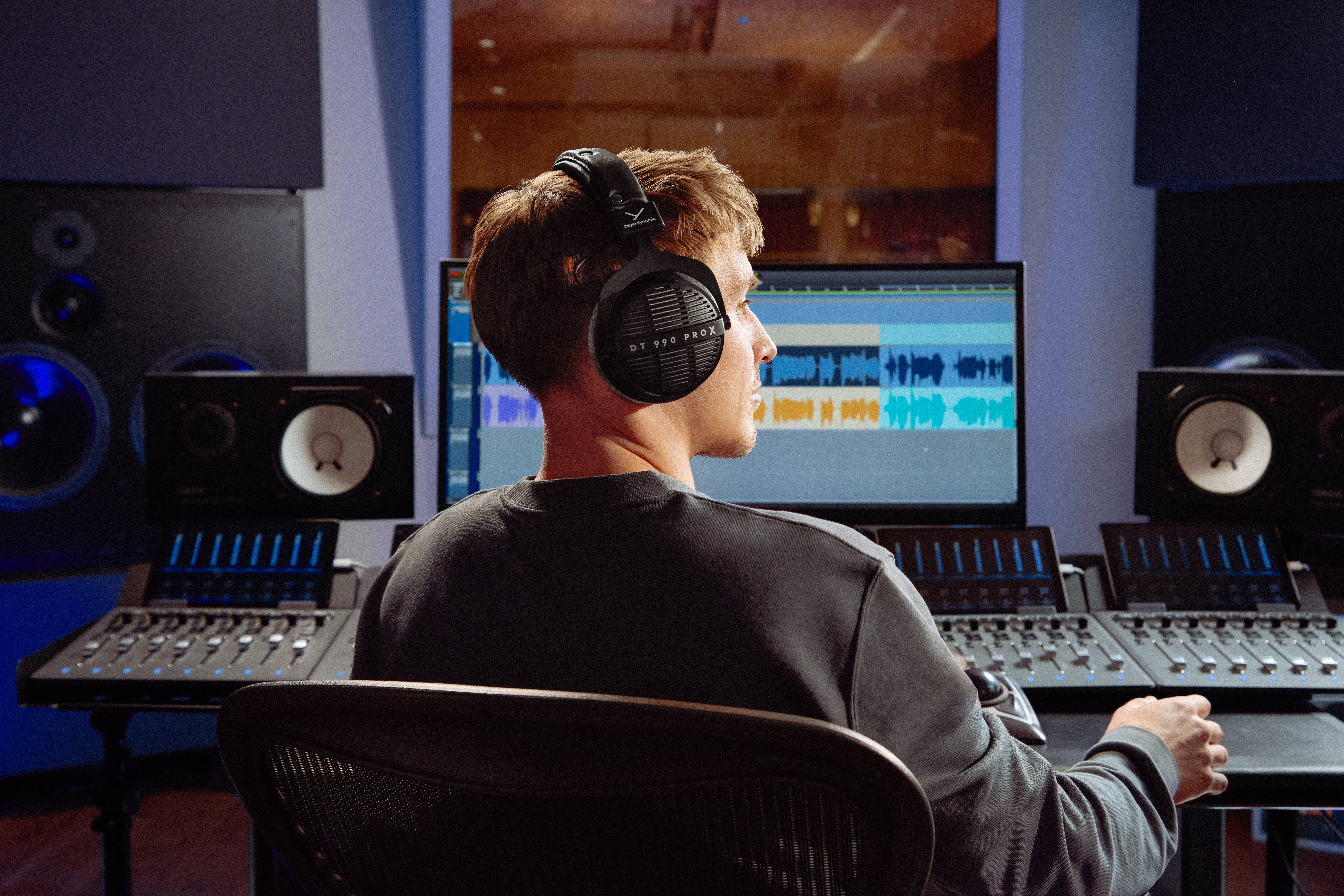 A man wearing the Beyerdynamic DT 990 PRO X headphones in a music studio.