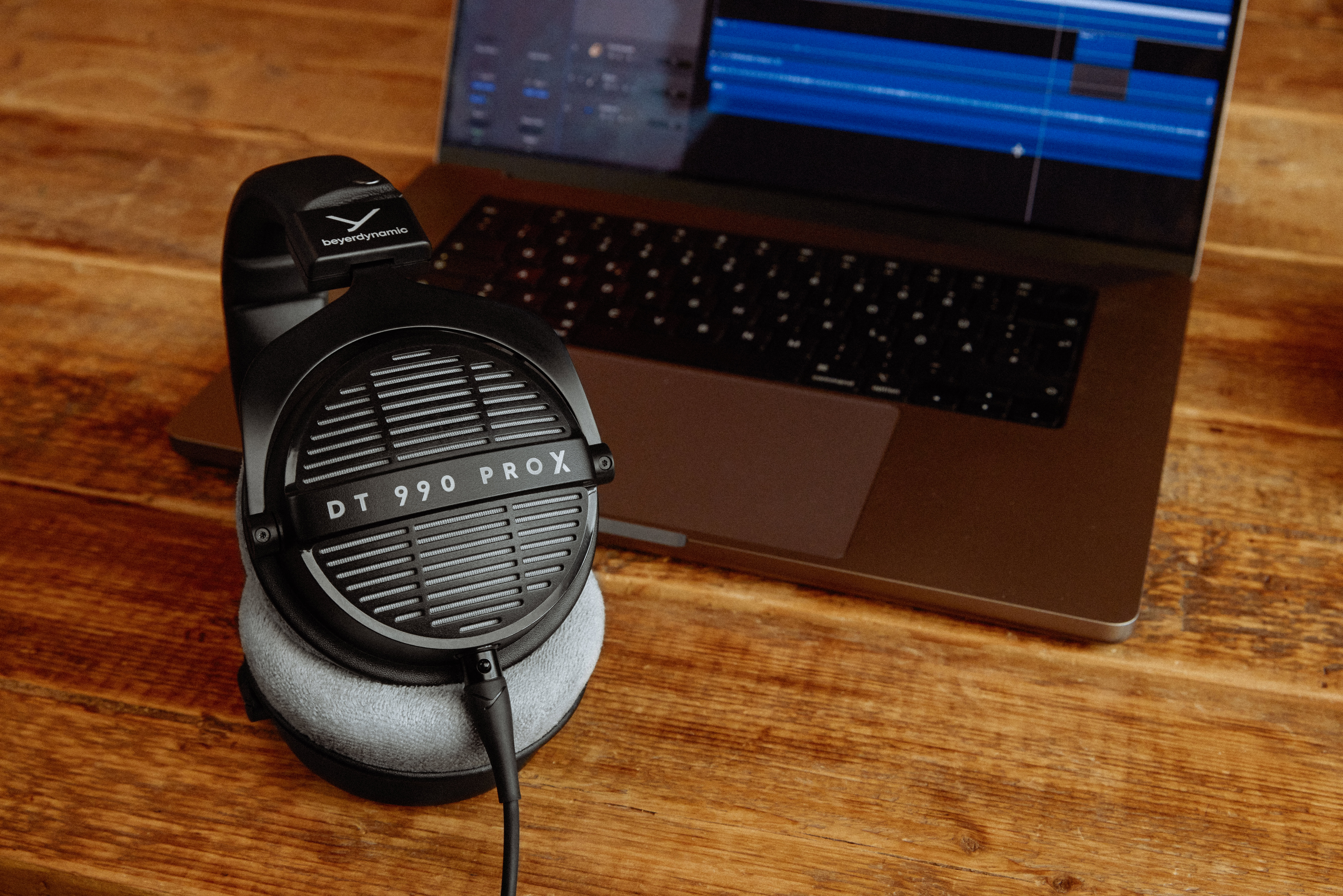 The Beyerdynamic DT 990 PRO X headphones next to a laptop.