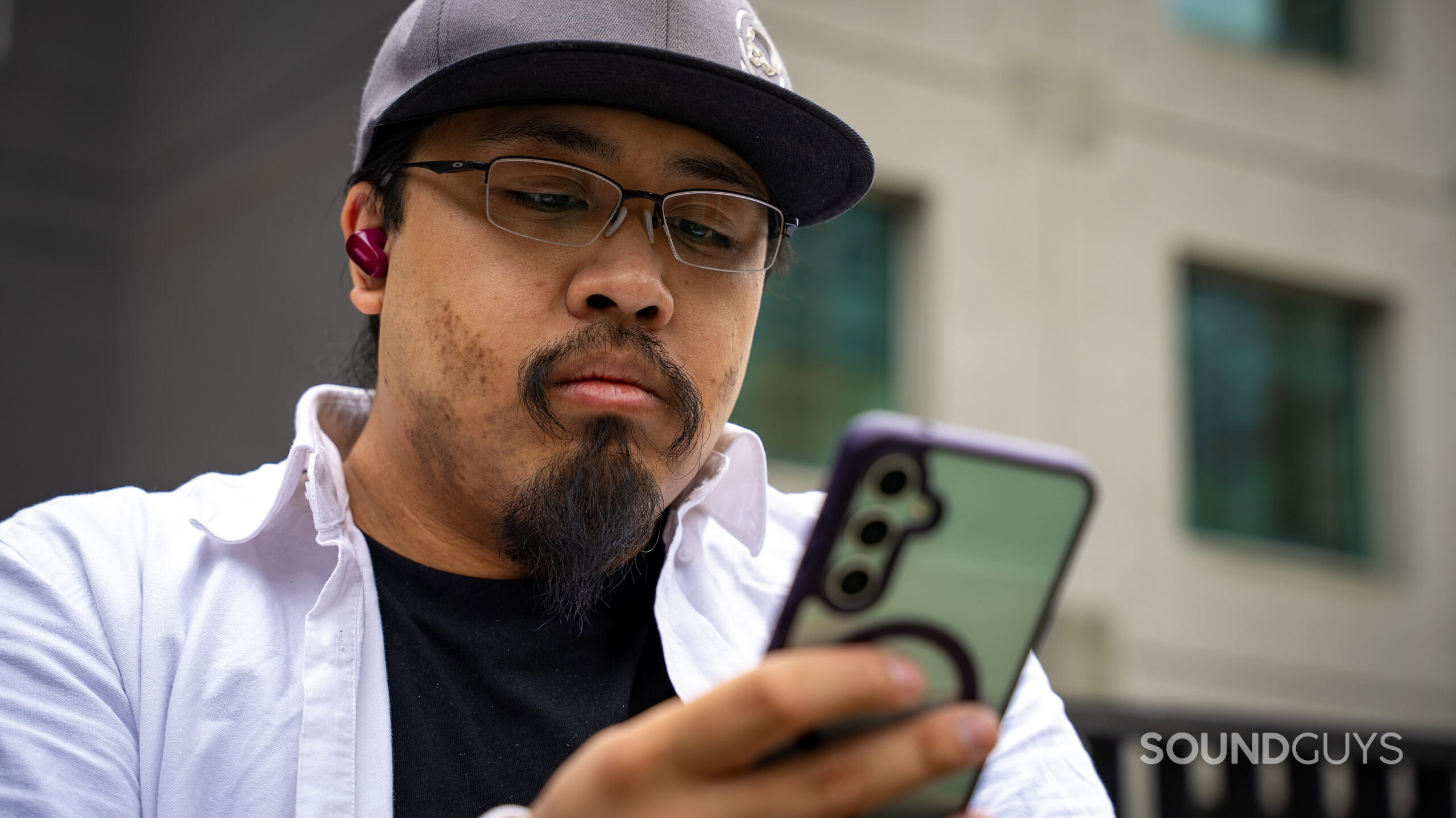 Bose QuietComfort Ultra Earbuds (2nd Gen)_32 A photo of a man listening to the Bose QuietComfort Ultra Earbuds (2nd Gen.), using a phone to control playback.