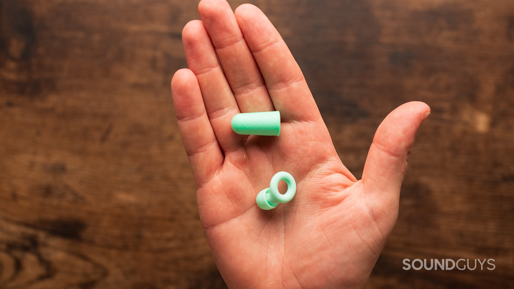Foam earplugs vs Loop earplugs A hand holding Loop Earplugs and regular foam earplugs.