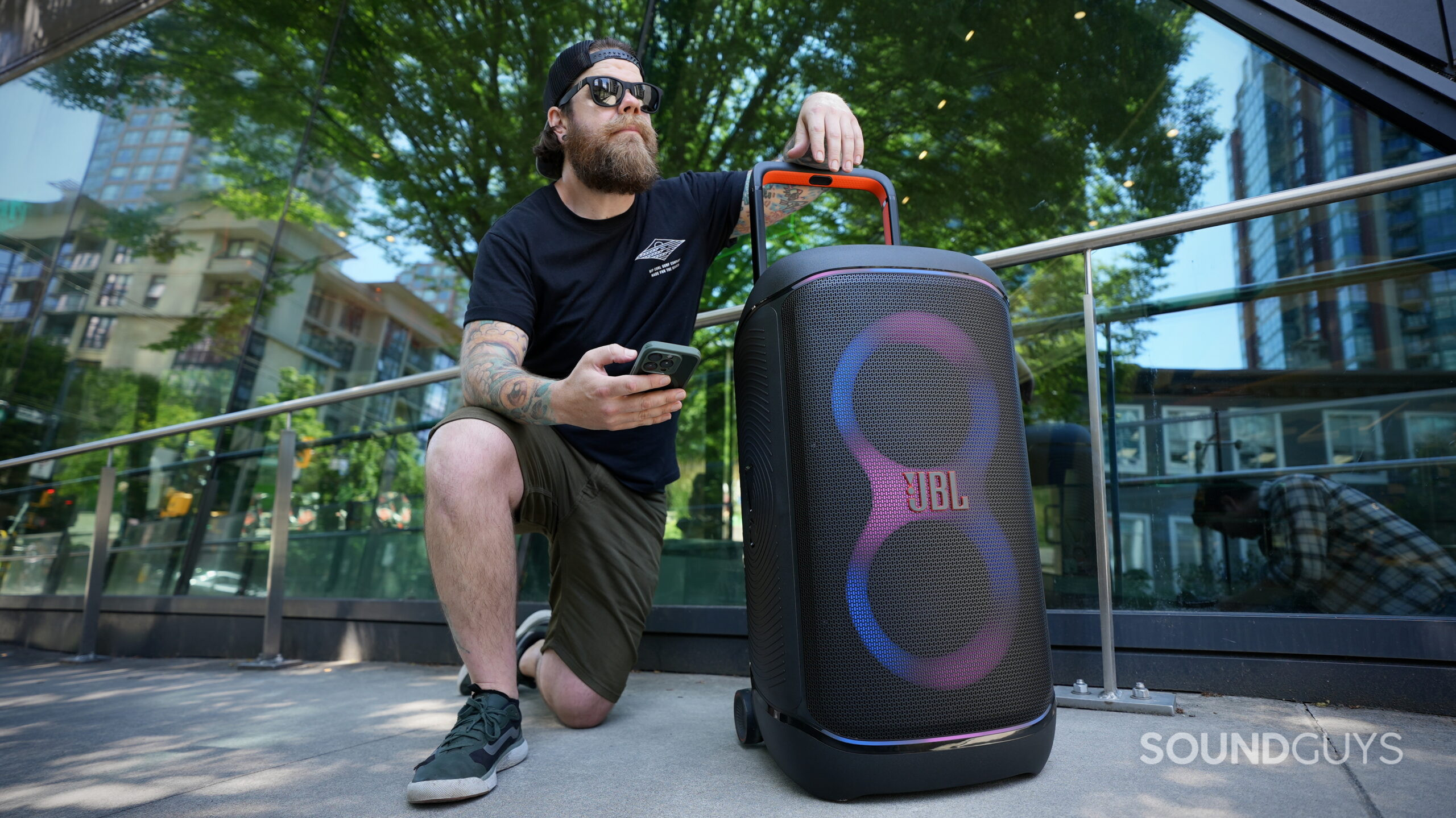 JBL 520_6 A man kneeling beside a JBL PartyBox 520 in a city setting.