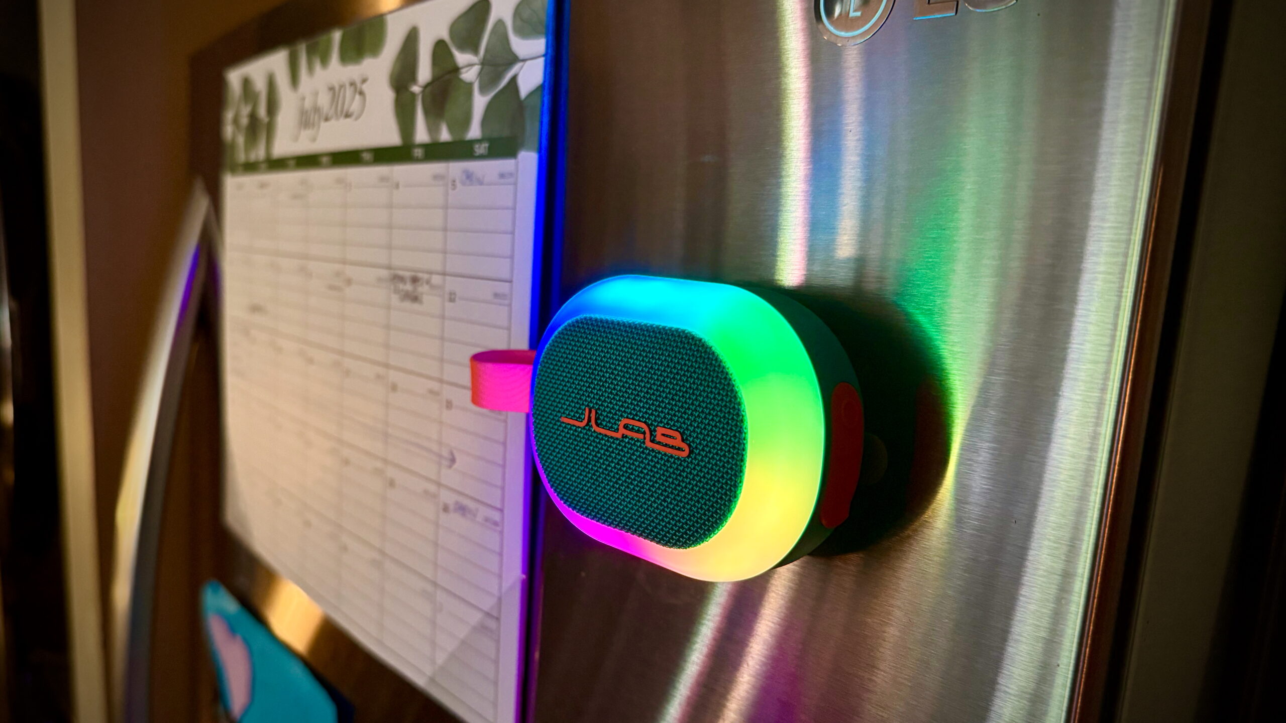 JLab Pop Party - 8 A JLab Pop Party with its RGB lights on, stuck magnetically to a fridge.