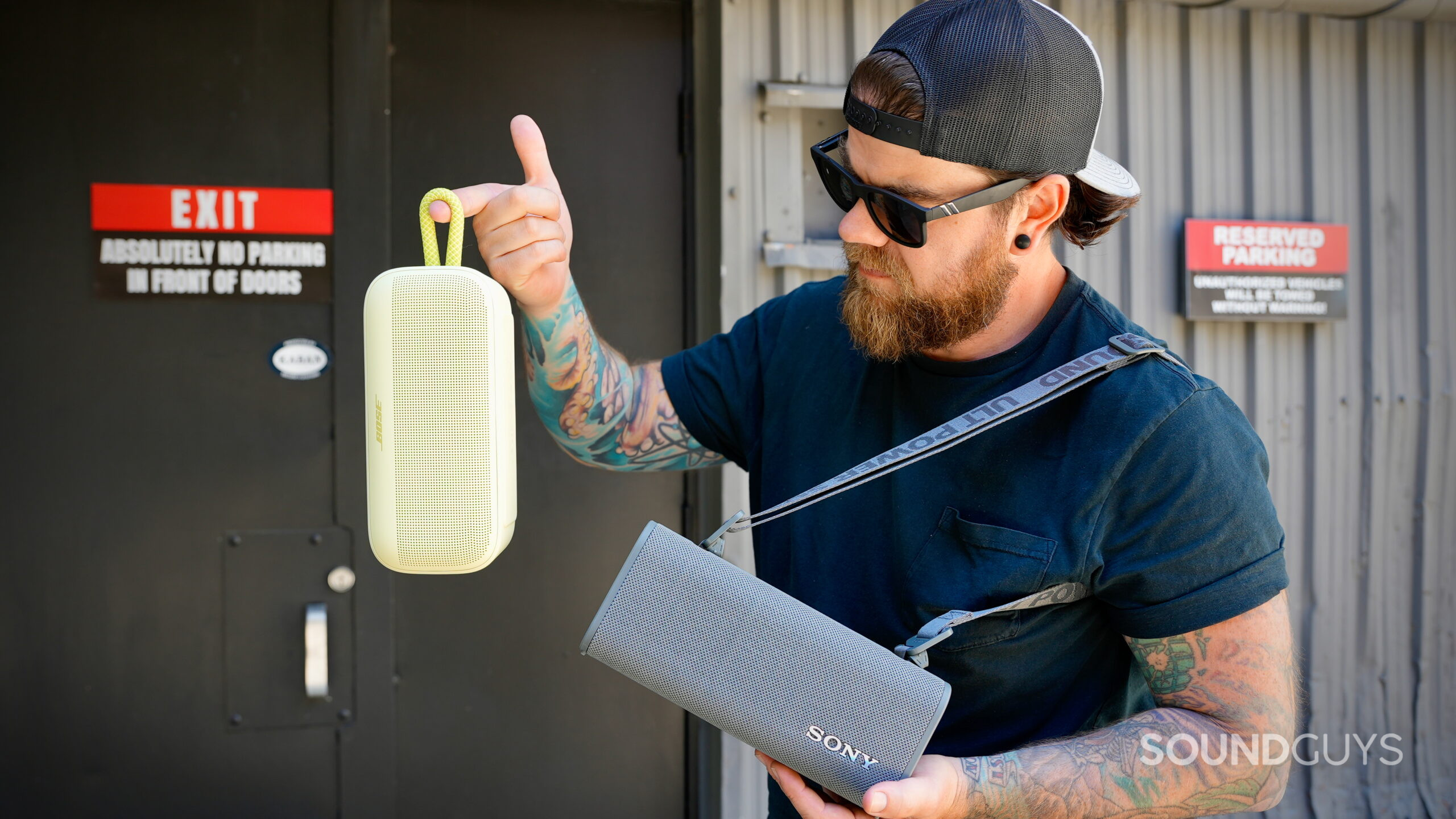 SL Plus Vs ULT Field 3 - 3 A man holding the Bose SoundLink Plus and Sony ULT Field 3 by their attachment options.