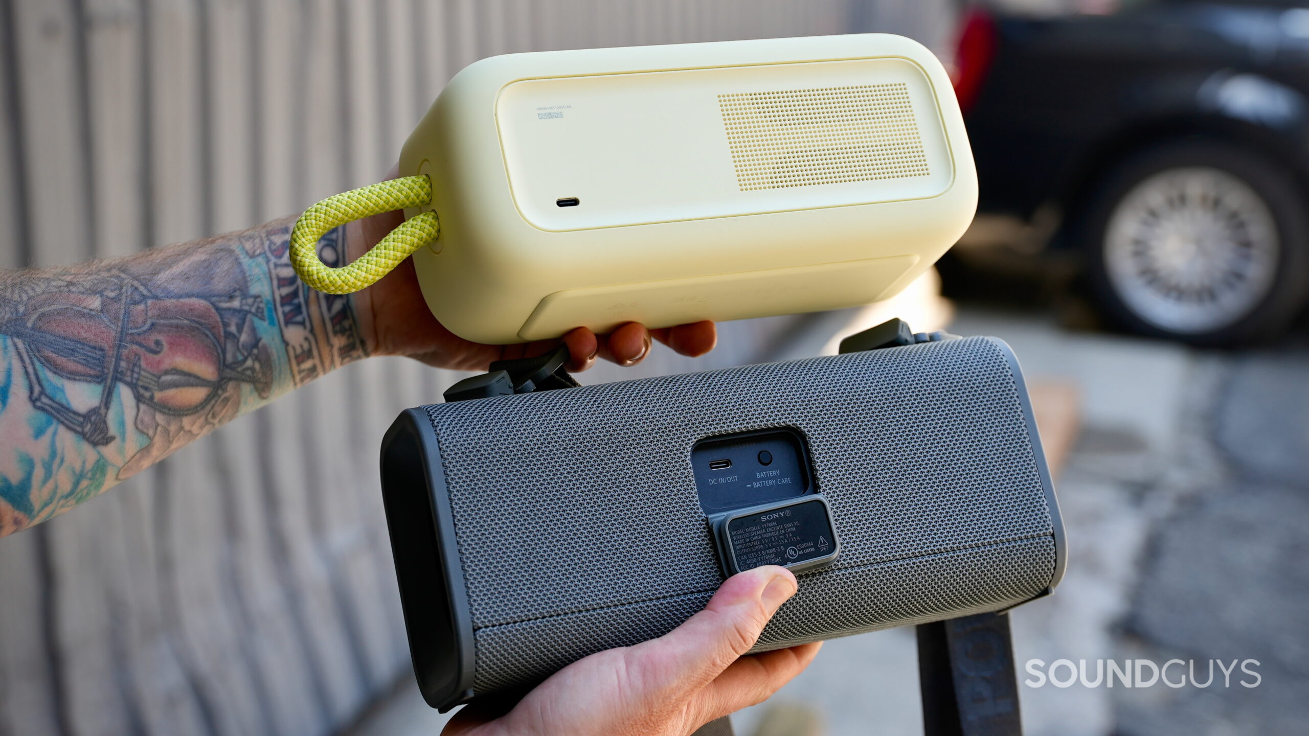 SL Plus Vs ULT Field 3 - 6 A man holding the Bose SoundLink Plus and Sony ULT Field 3 together, showing their rear ports.