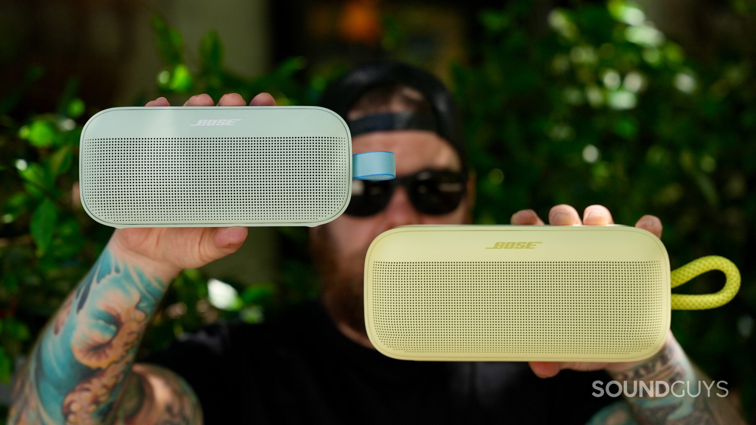 SL Plus vs Flex - 1 A man holds the Bose SoundLink Plus and SoundLink Flex in front of his face.