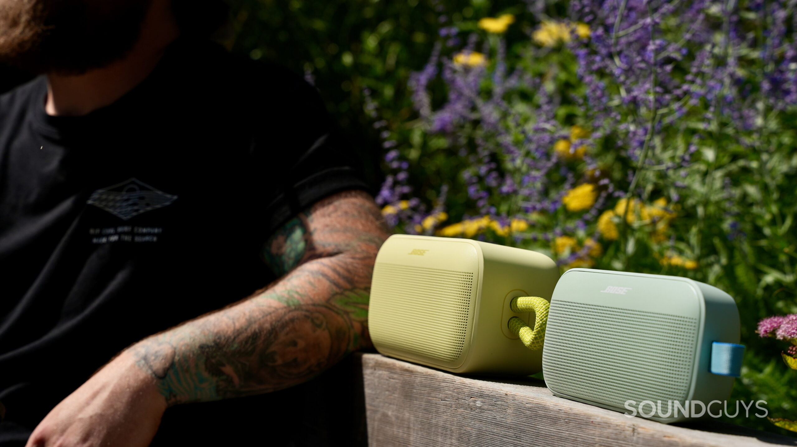 SL Plus vs Flex - 7 A man sitting next to a Bose SoundLink Plus and SoundLink Flex on a park bench.