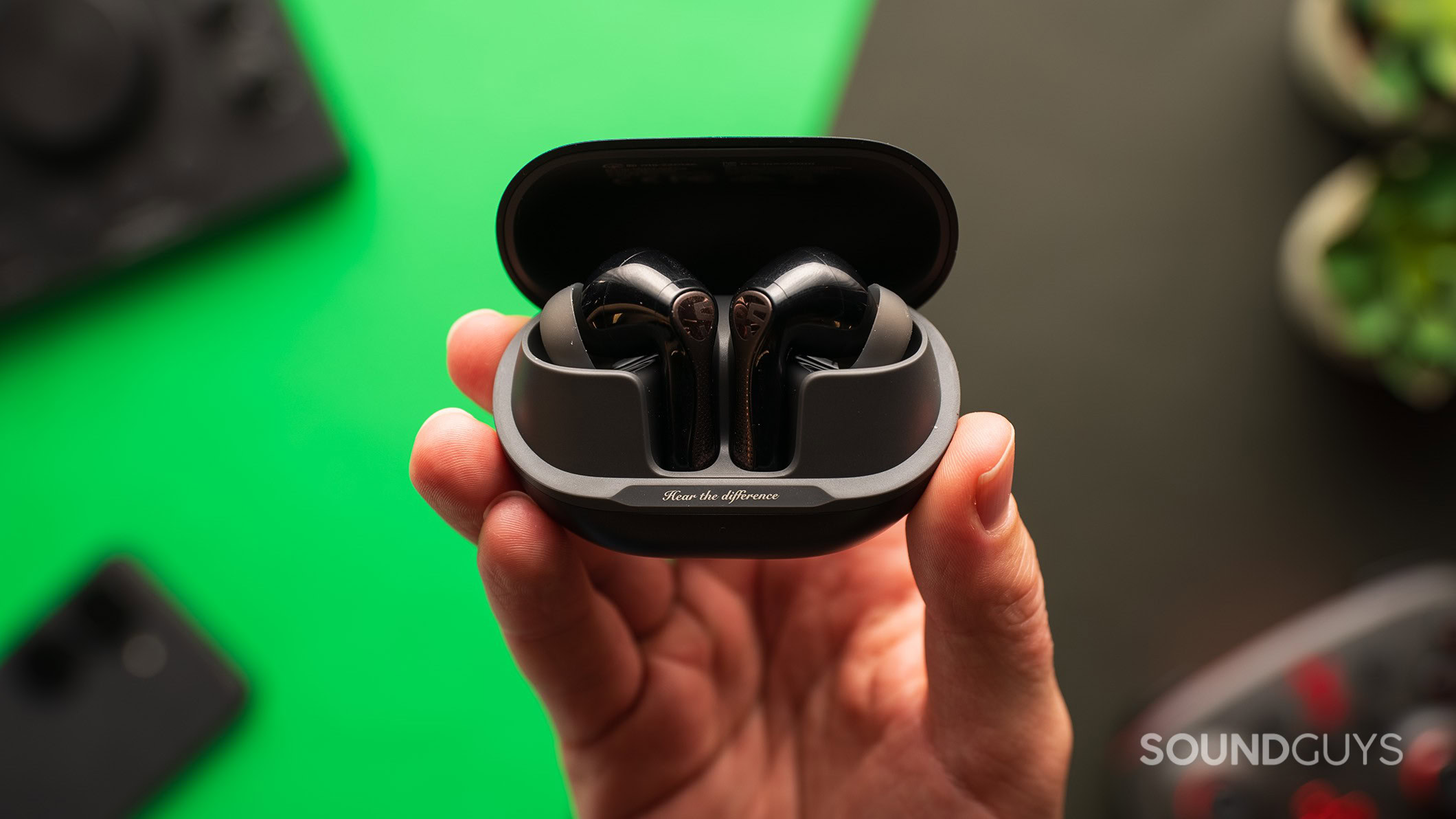 A hand holding a SOUNDPEATS Air5 Pro earbuds case.