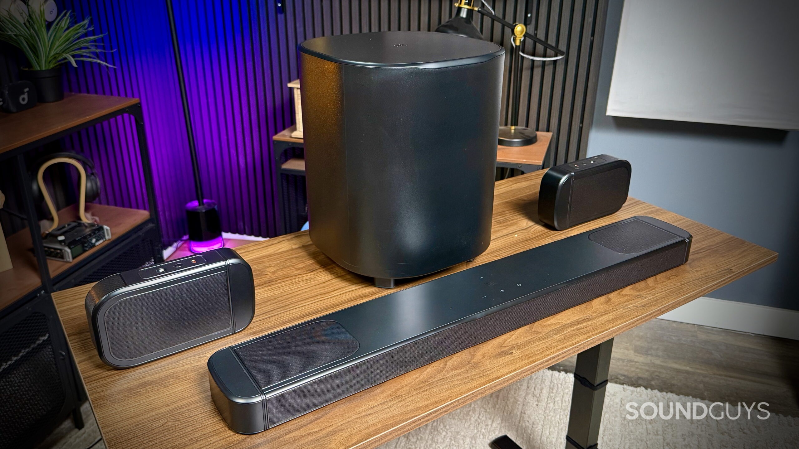 JBL Bar 1000MK2 - 7 Full view of the JBL BAR 1000MK2 soundbar, detachable speakers, and wireless subwoofer arranged on a wooden desk.