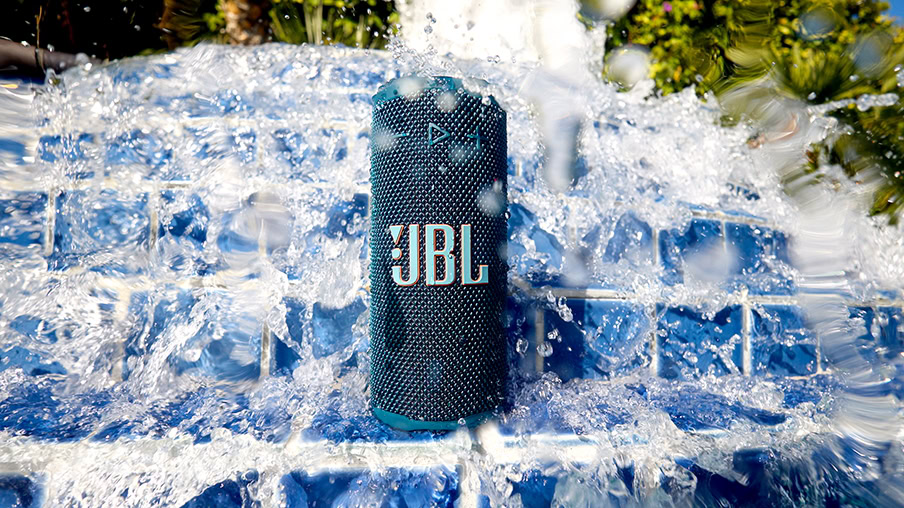 JBL Grip - 2 A JBL Grip speaker with a wave of water crashing onto it from behind.