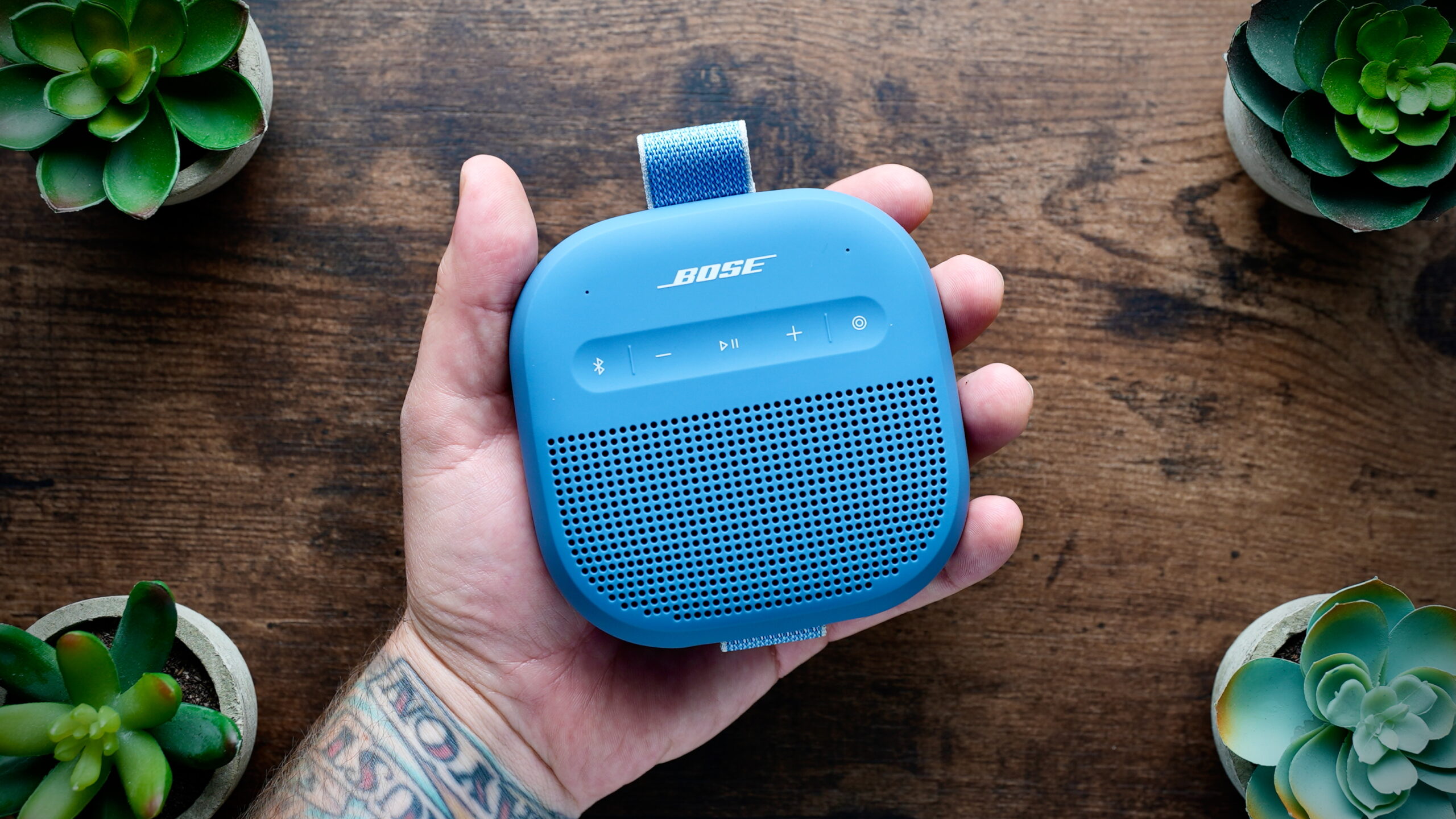A hand holds the Bose SoundLink Micro 2nd Gen