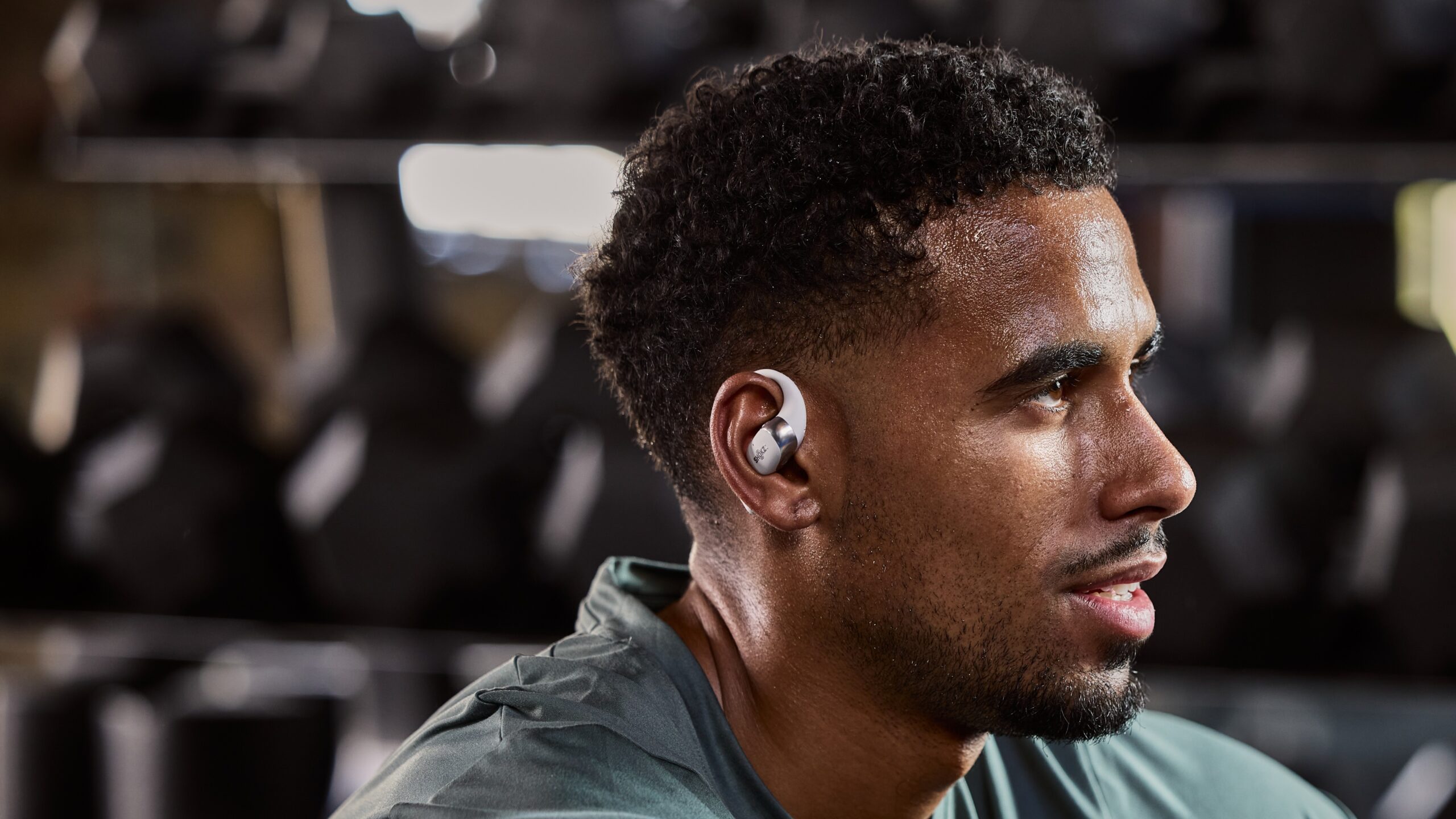 a man wearing the shokz openfit 2 at the gym