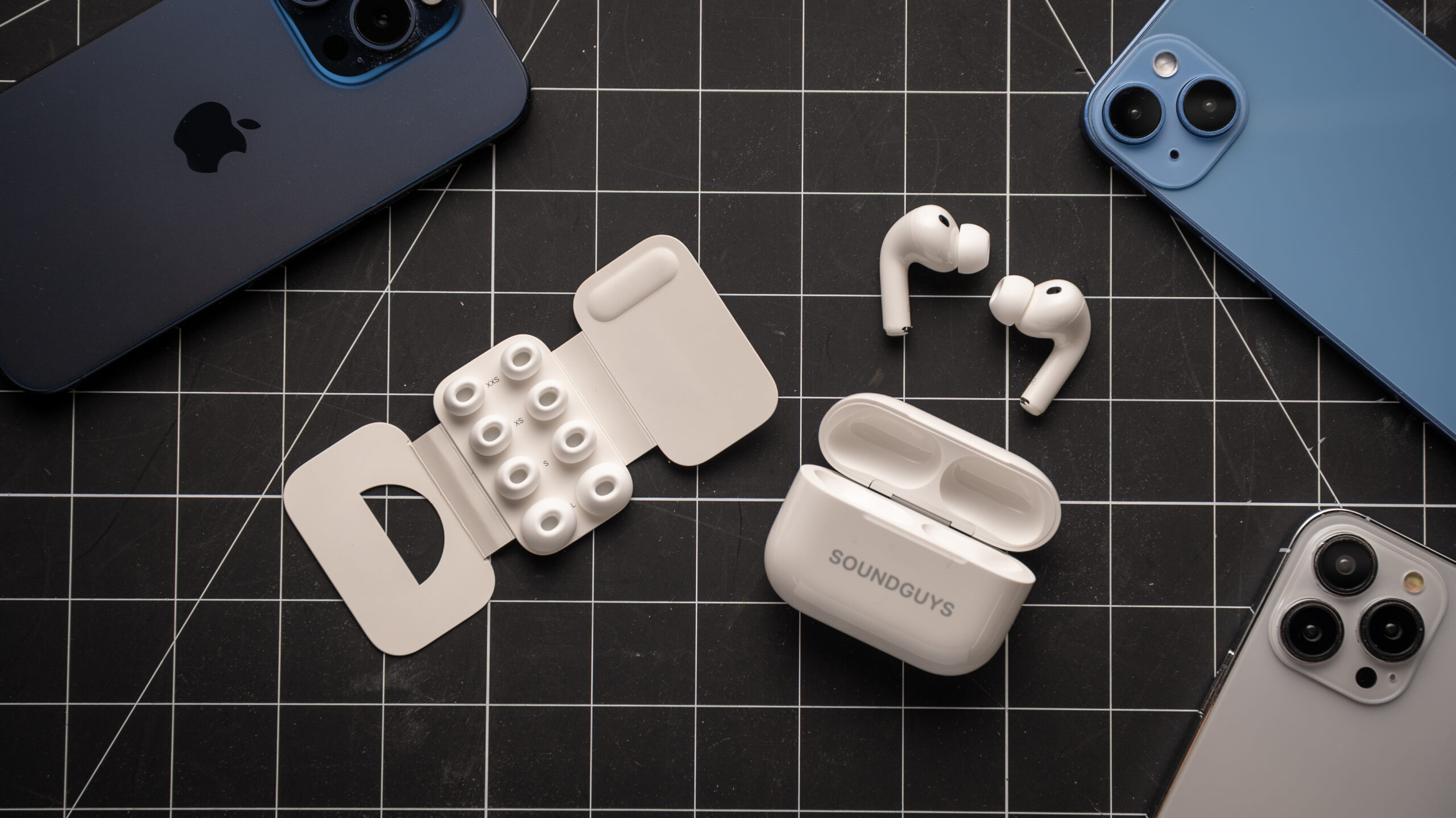 AirPods Pro 3 earbuds outside of charging case next to different foam-infused ear tip sizes on table