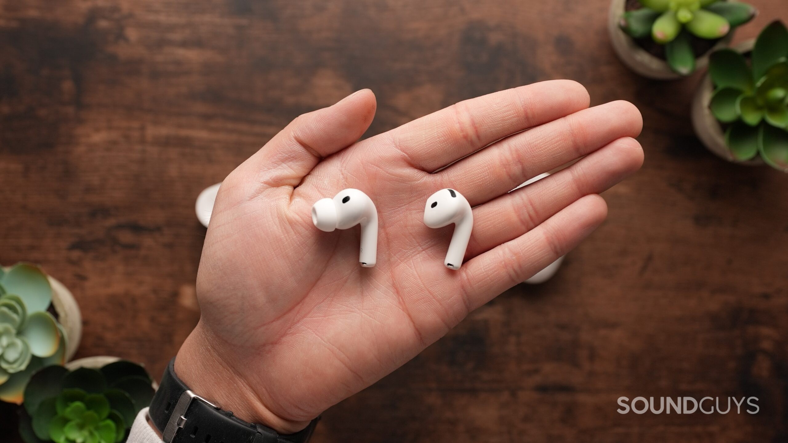 The AirPods Pro 3 and AirPods 4 sit on a table. Each right earbud sits in the centre.