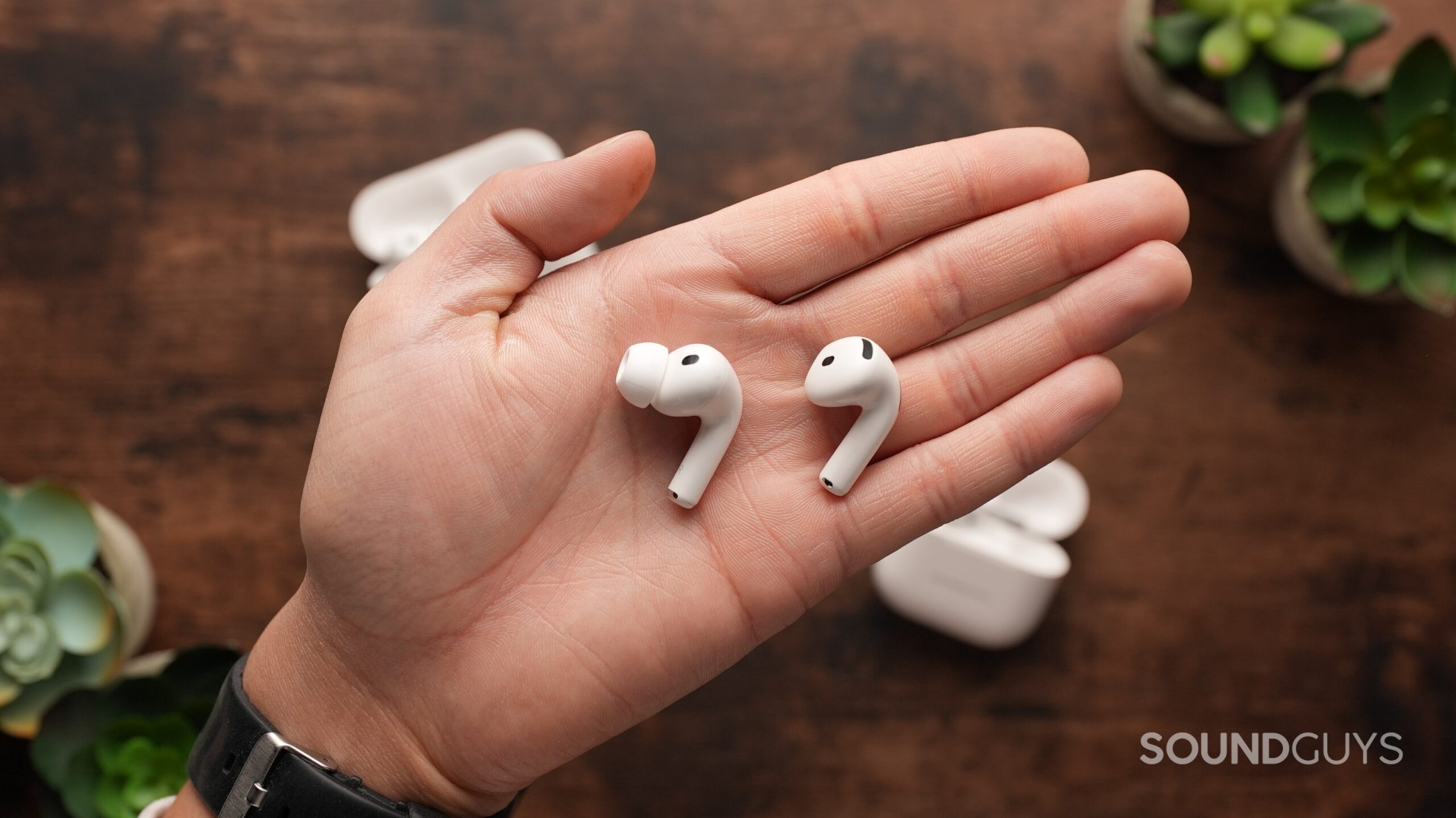 The AirPods Pro 3 and AirPods 4 sit on a table. Each right earbud sits in the centre.