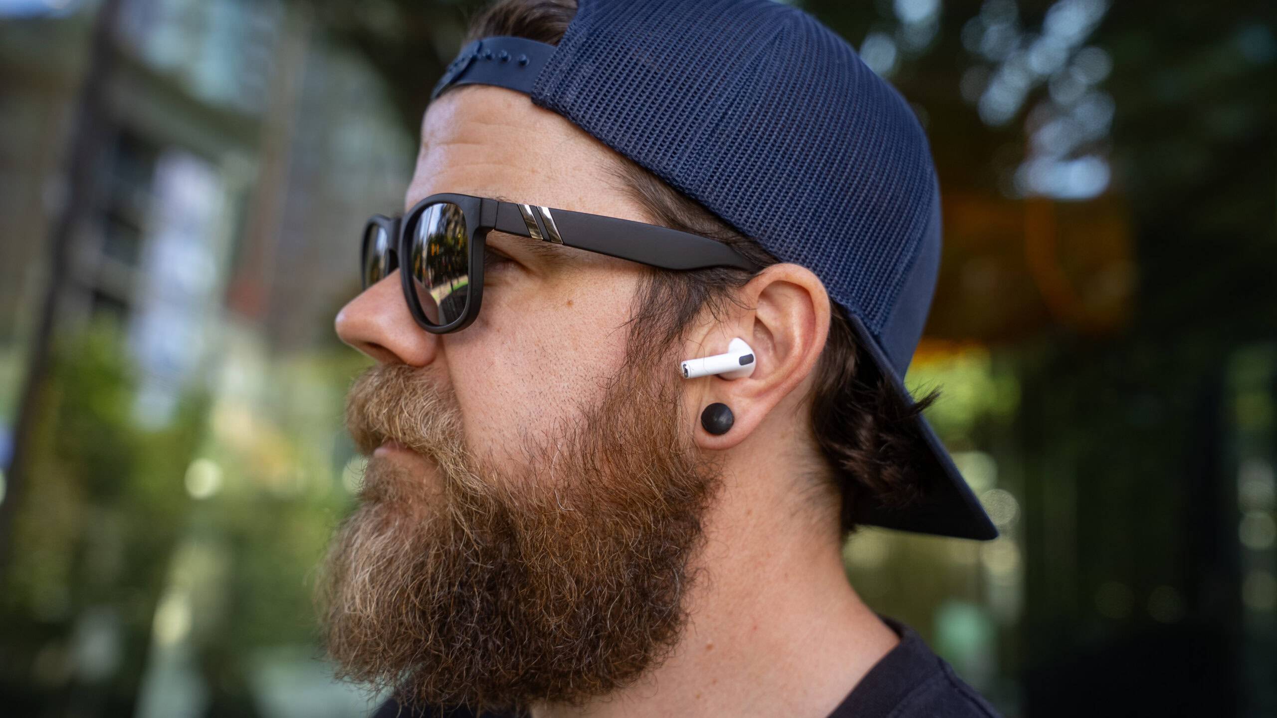 apple-airpods-pro-3-close-man-wearing-earbuds a man wearing the airpods pro 3 outdoors