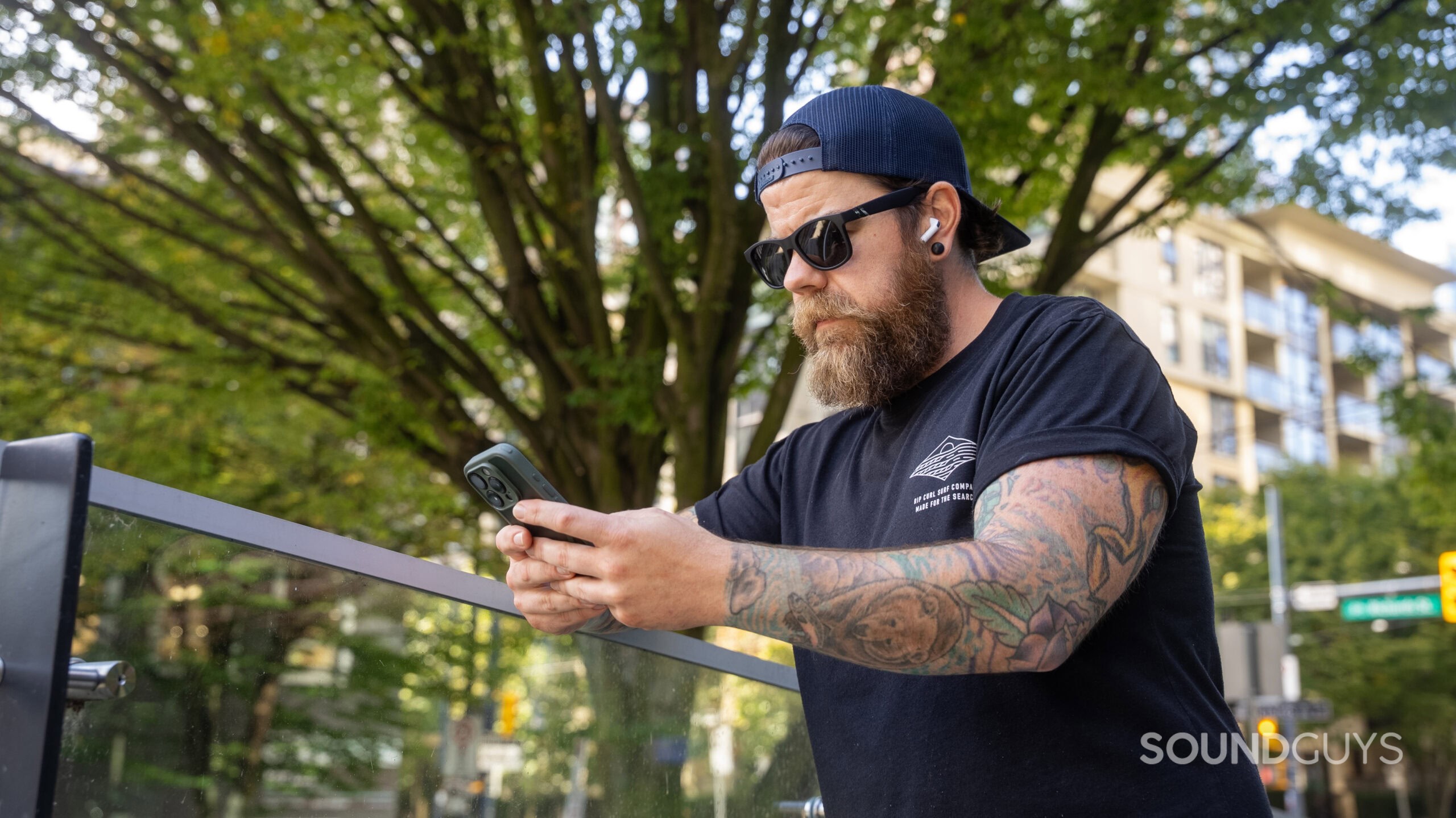 Wide shot of man wearing AirPods Pro 3 while on his iPhone.