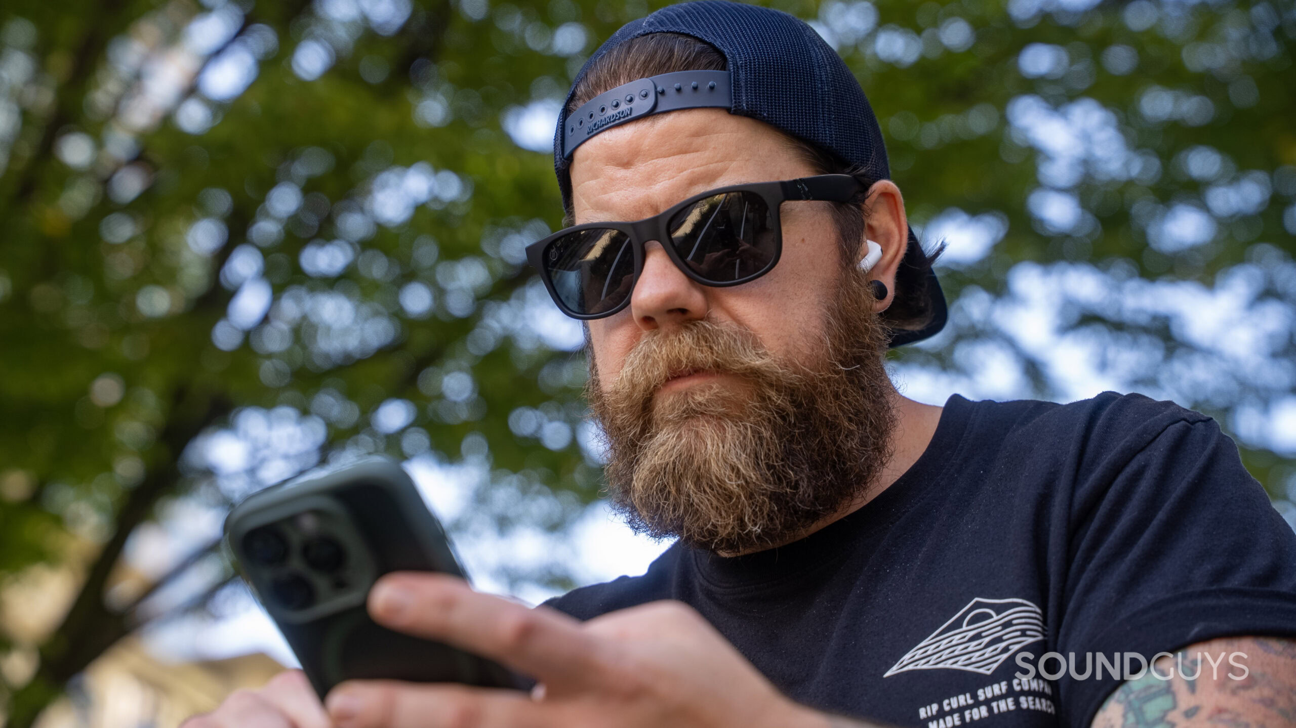 A person wearing AirPods Pro and using an iPhone to adjust audio settings.