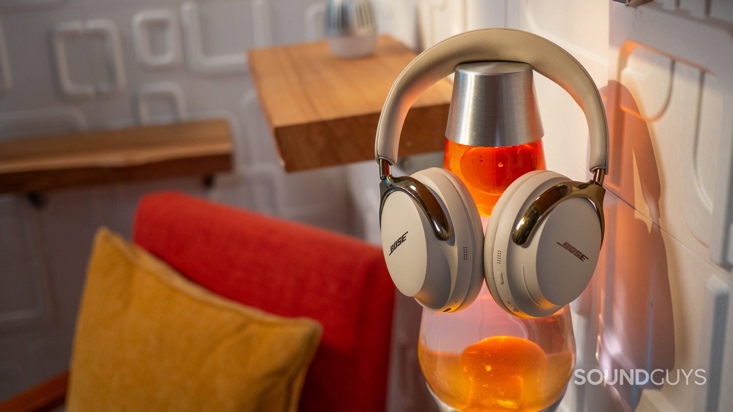 The Bose QuietComfort Ultra (2nd Gen.) sitting on a lava lamp, in a 1970s-inspired scene.