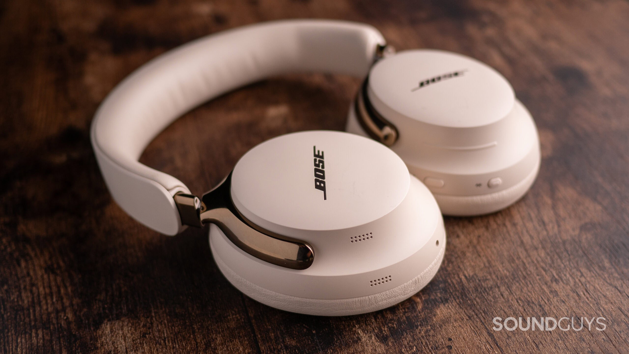 The Bose QuietComfort Ultra (2nd Gen.) laying flat atop a wooden desk.