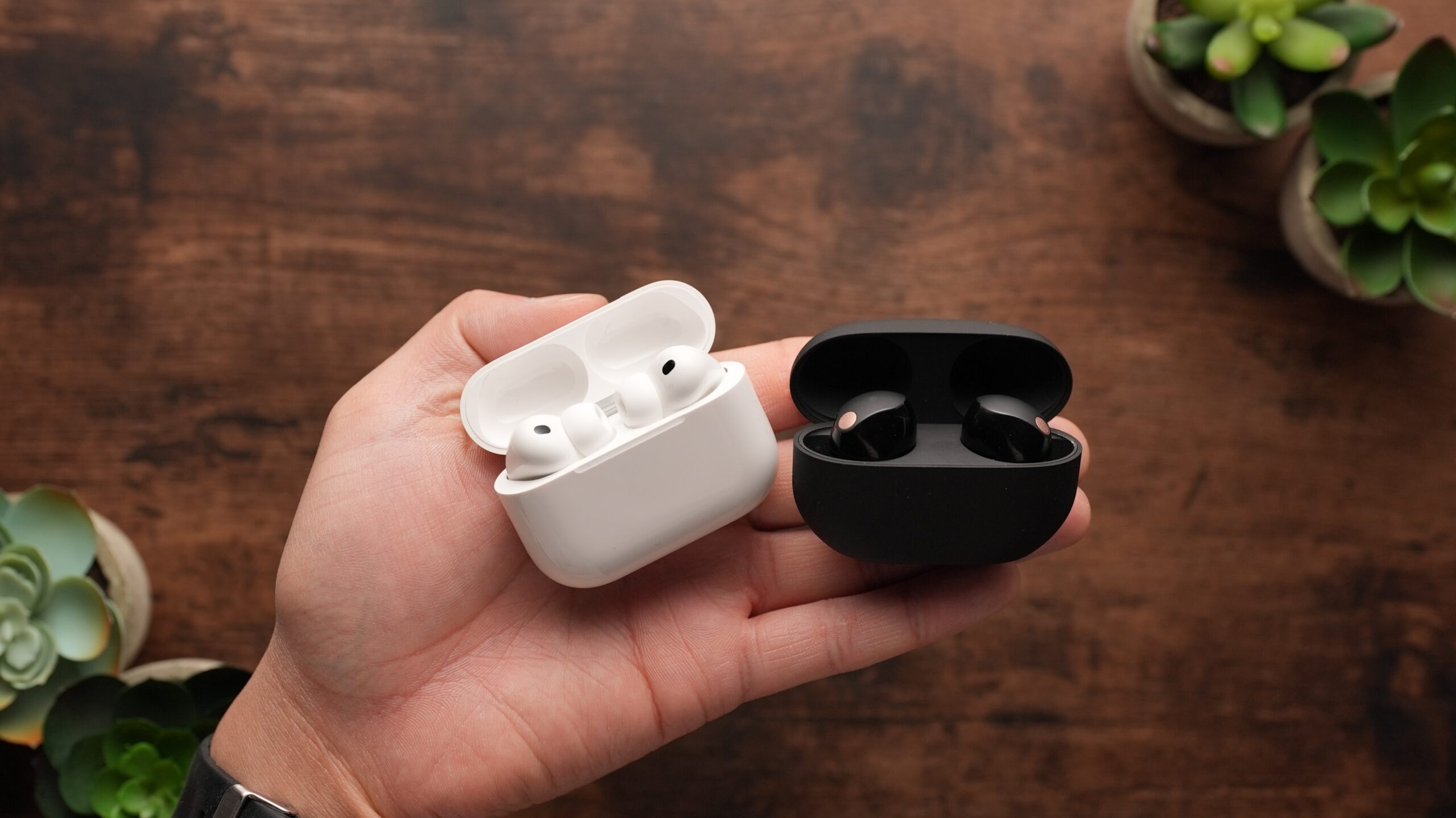 The AirPods Pro 3 and th Sony WF-1000XM5s sit on a table.