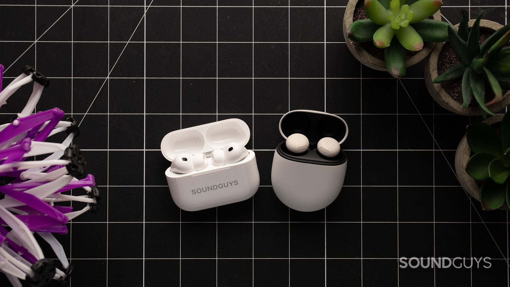 Apple AirPods Pro 3 next to the Google Pixel Buds Pro 3 on a table with the earbuds in their case.