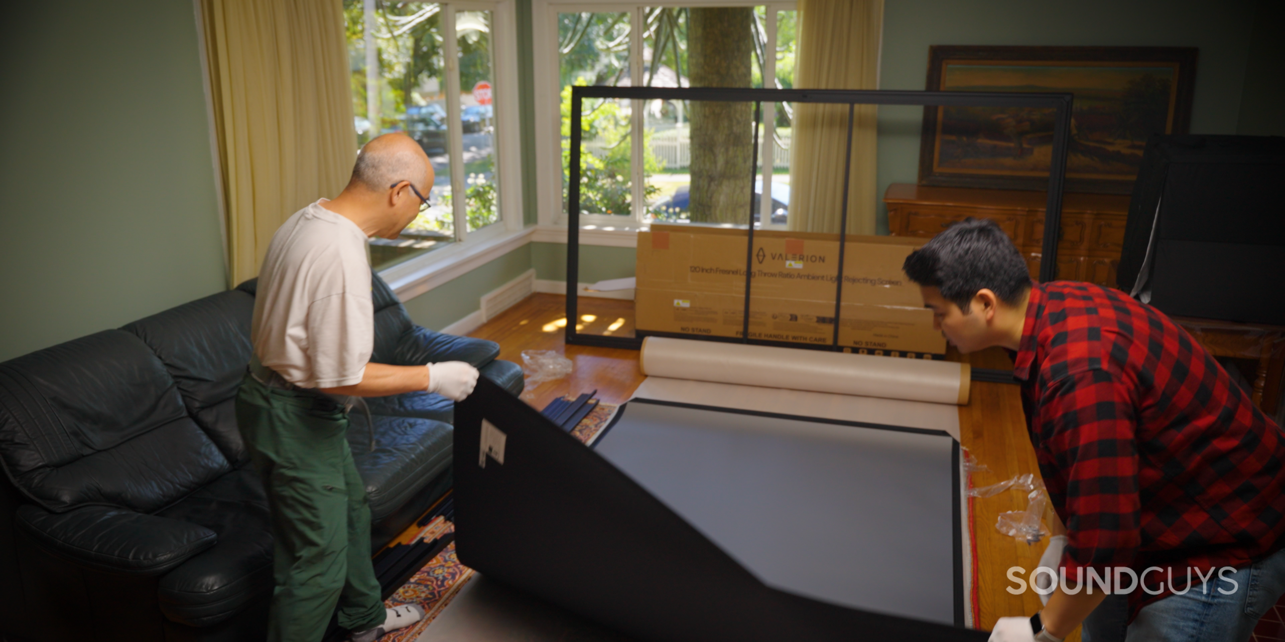 SG_Valerion VisionMaster Pro 2-17 Two men setting up Valerion 120" Fresnel Ambient Light Rejecting Screen in living room
