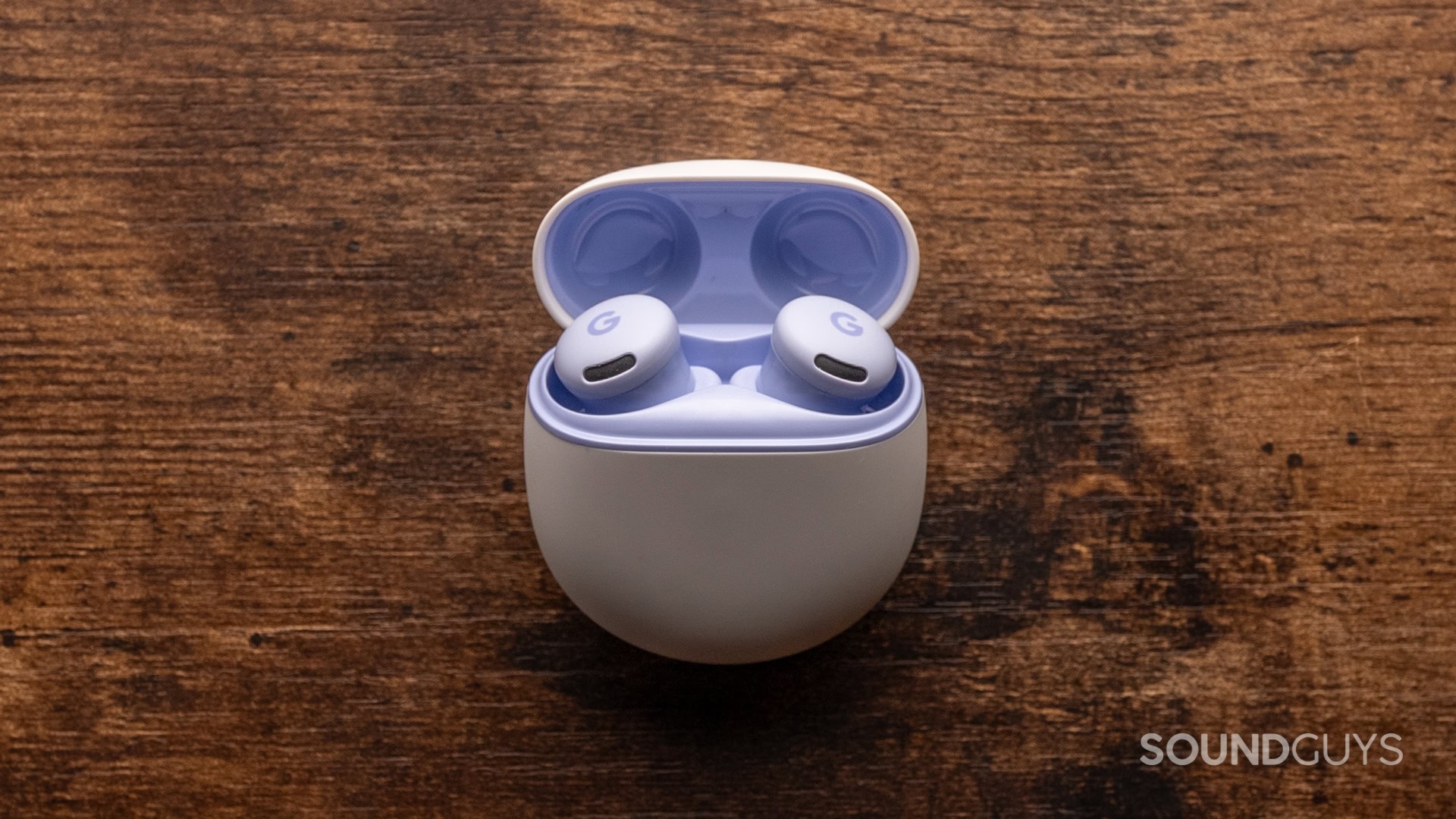 A photo of the purple Google Pixel Buds 2a atop a wooden desk.