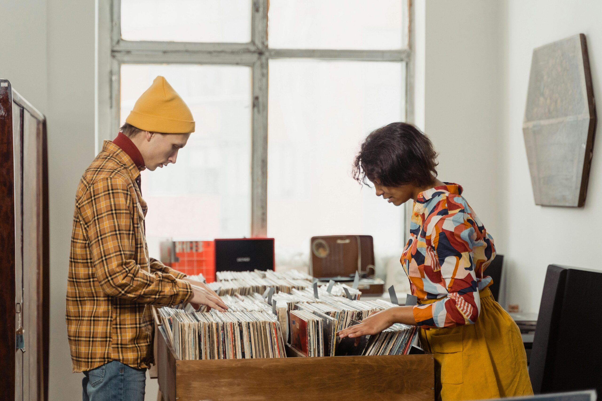 pexels-tima-miroshnichenko-6827191 Two people stand opposite each other, flicking through bins of records